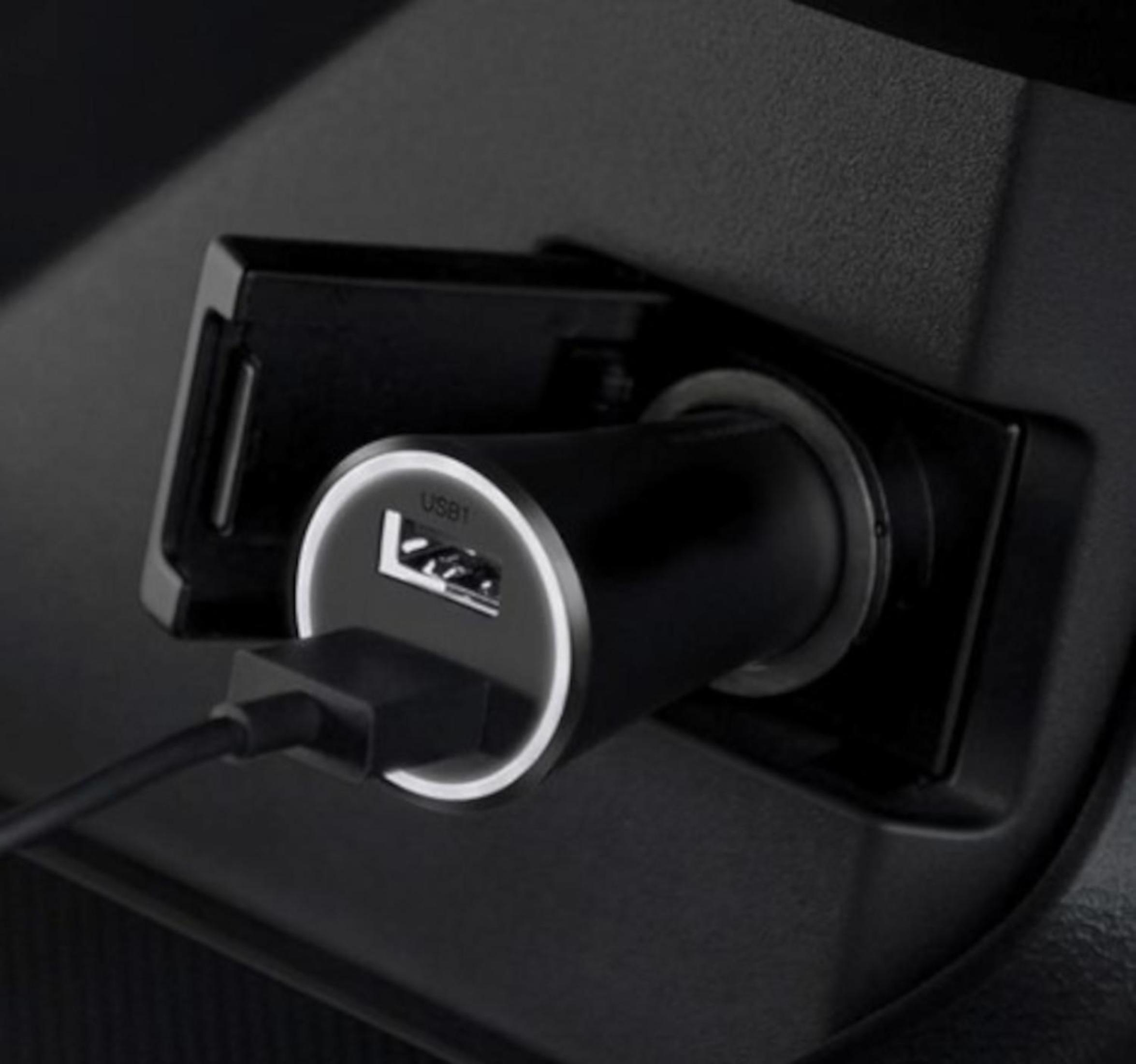 Ładowarka samochodowa z podłączonym portem USB, we wnętrzu czarnego samochodu.