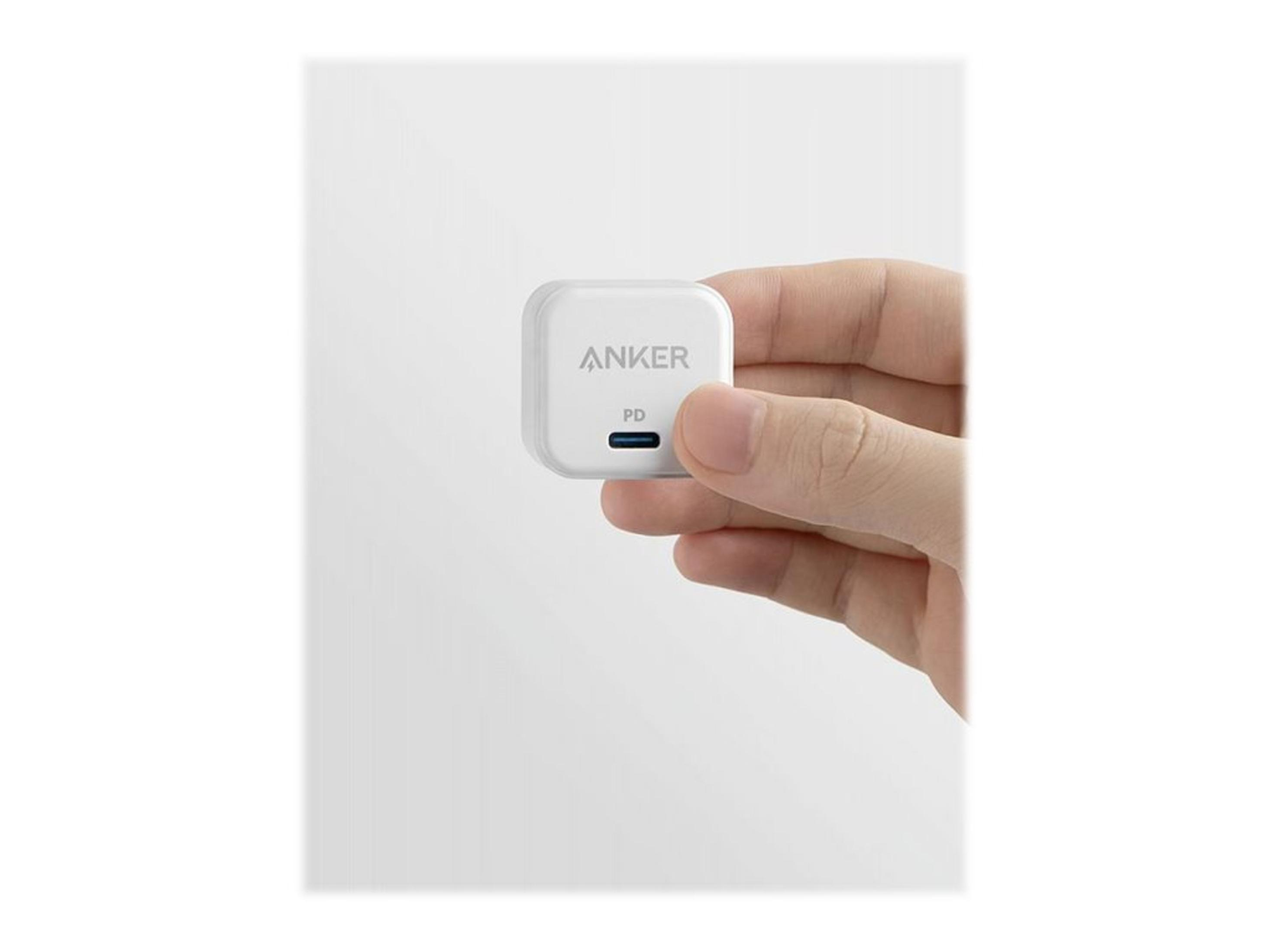 Caricatore Anker bianco, tenuto in mano. Testo: Anker PD e una porta USB-C blu. Sfondo bianco.