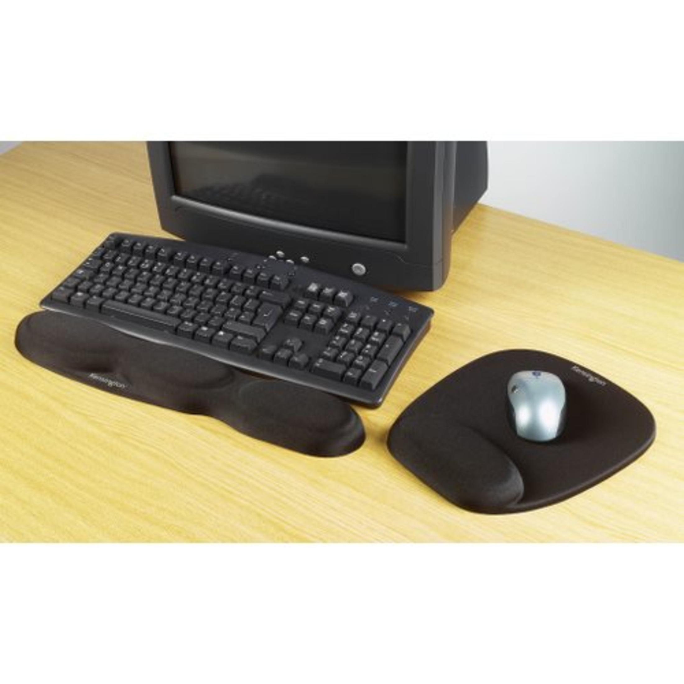 Una configuración de escritorio con un teclado, un ratón y una alfombrilla de ratón. La configuración está sobre un escritorio de madera.
