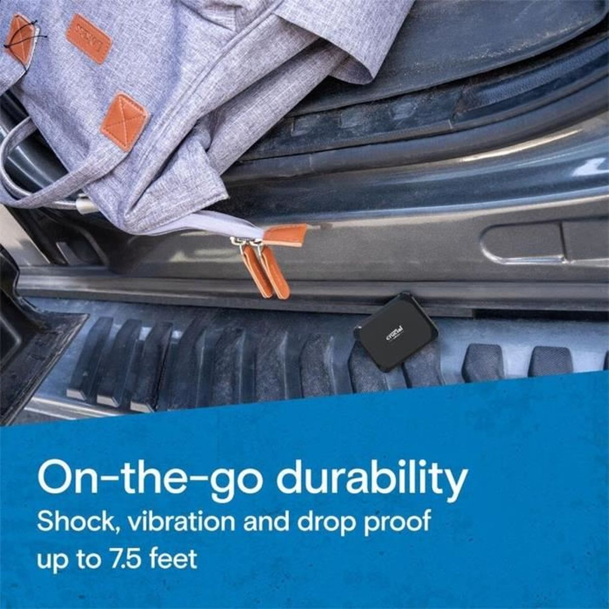 Szary plecak i czarne, małe urządzenie śledzące na podłodze bagażnika samochodu. Nakładka tekstowa.