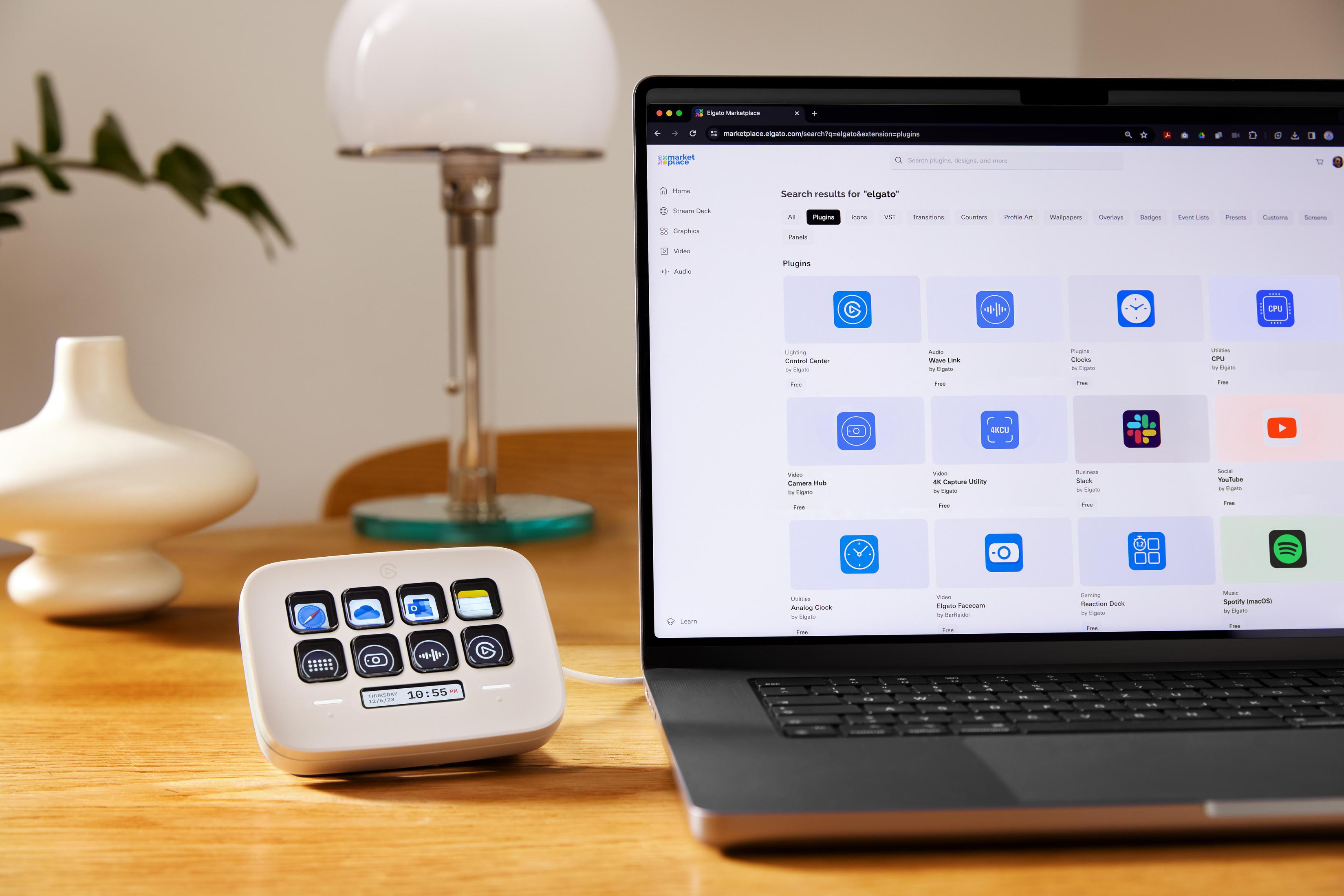 Ein Laptop mit Plugin-Oberfläche, Stream Deck und Schreibtischlampe auf einem Holztisch.