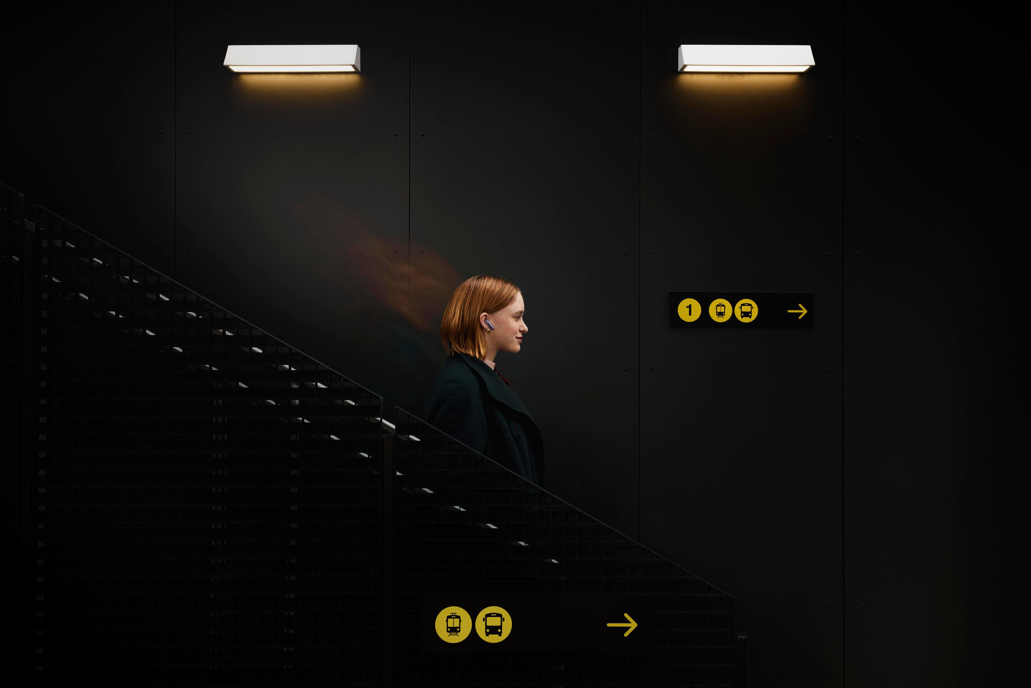 Frau auf Treppe mit gelbem Schild. Lichter oben.