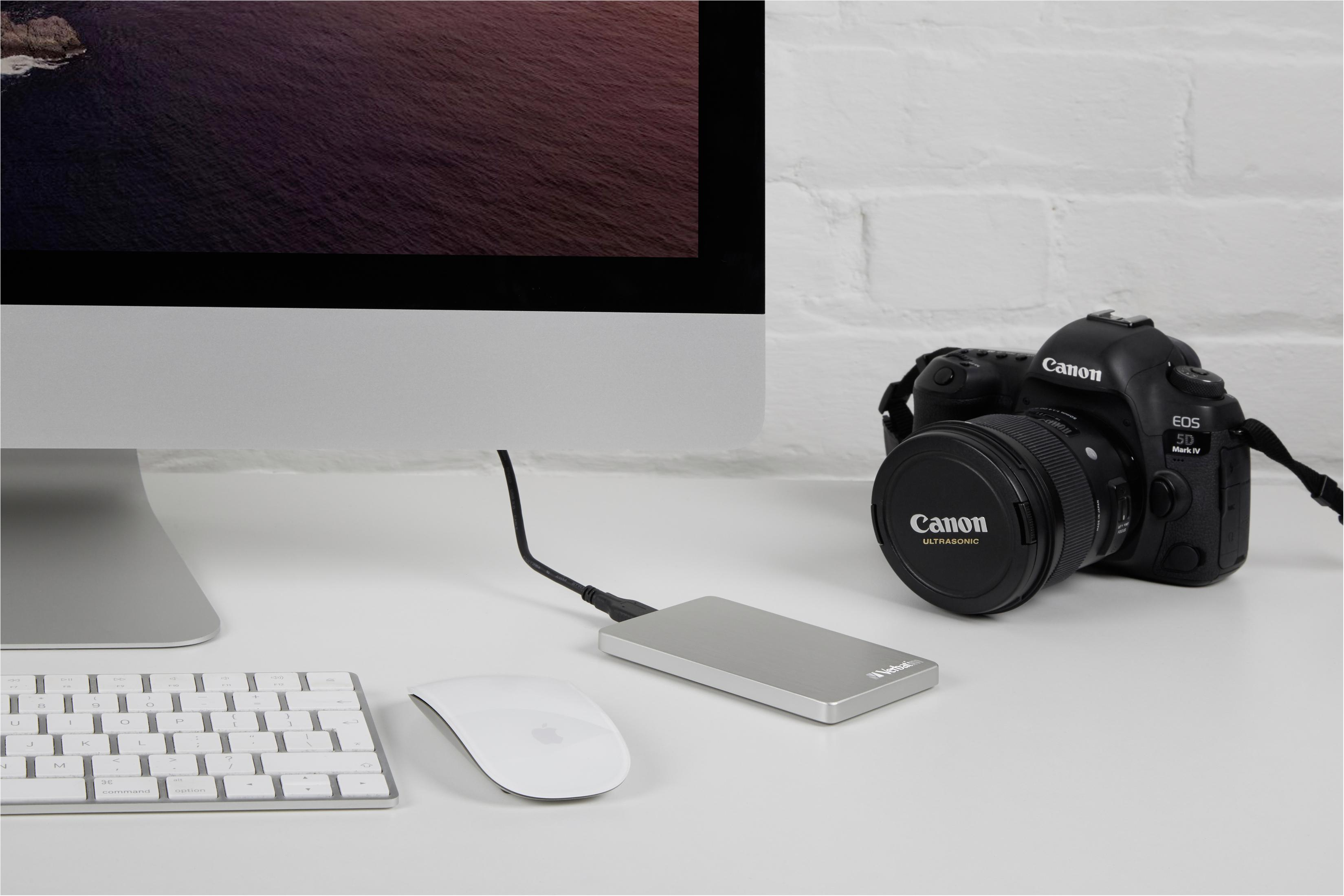 Konfiguracja komputera: monitor, klawiatura, mysz i zewnętrzny dysk twardy. Aparat Canon po prawej.