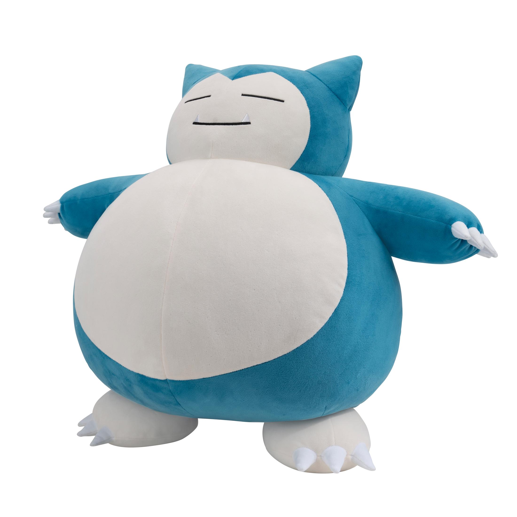 Ein großes Snorlax-Plüschtier, blau und weiß, steht mit ausgebreiteten Armen. Das Plüschtier steht vor weißem Hintergrund.