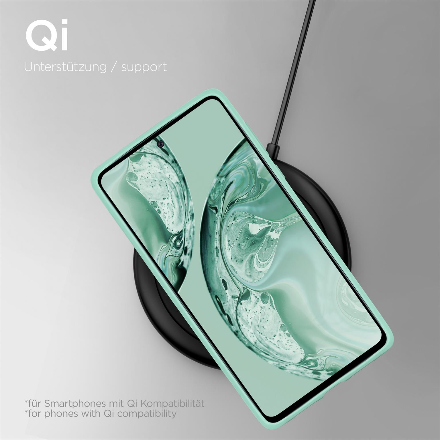 Ein Telefon in einem mintfarbenen Gehäuse wird auf einem schwarzen, kreisförmigen Ladepad geladen. Der Hintergrund ist hellgrau.