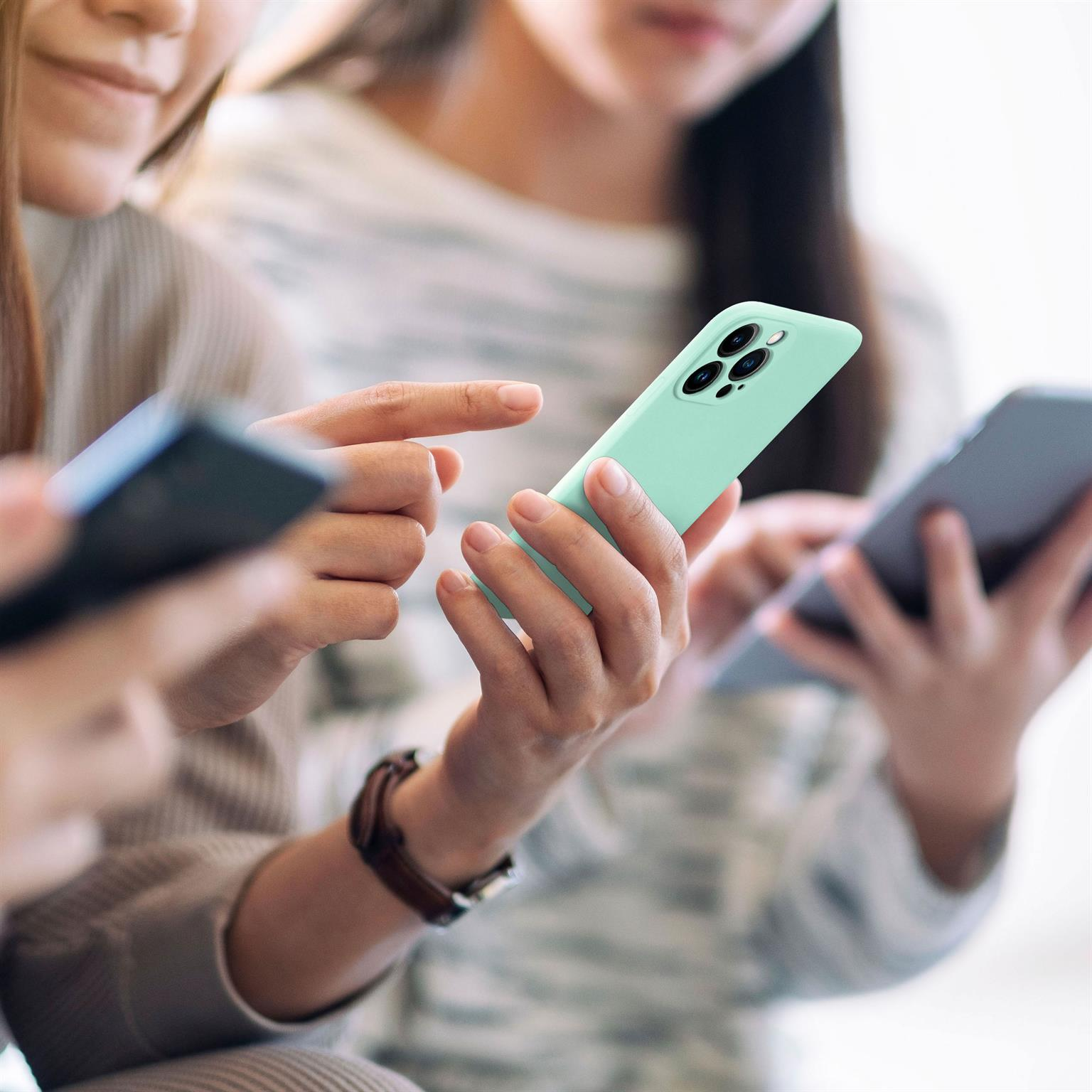 Personen halten Telefone, eines mit mintgrüner Hülle, und benutzen sie.