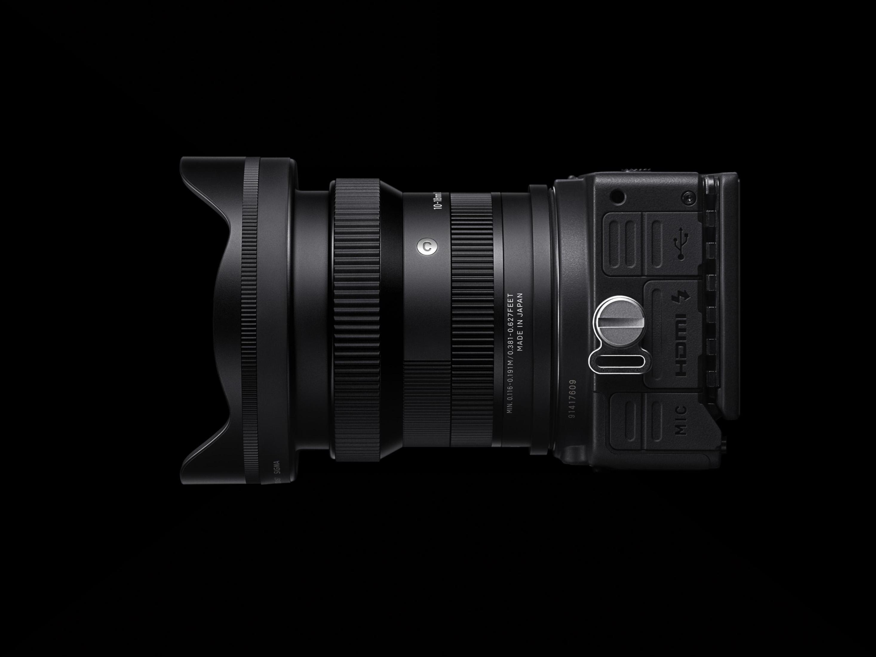 Czarny obiektyw i korpus aparatu, widok z boku na czarnym tle, szczegółowy.