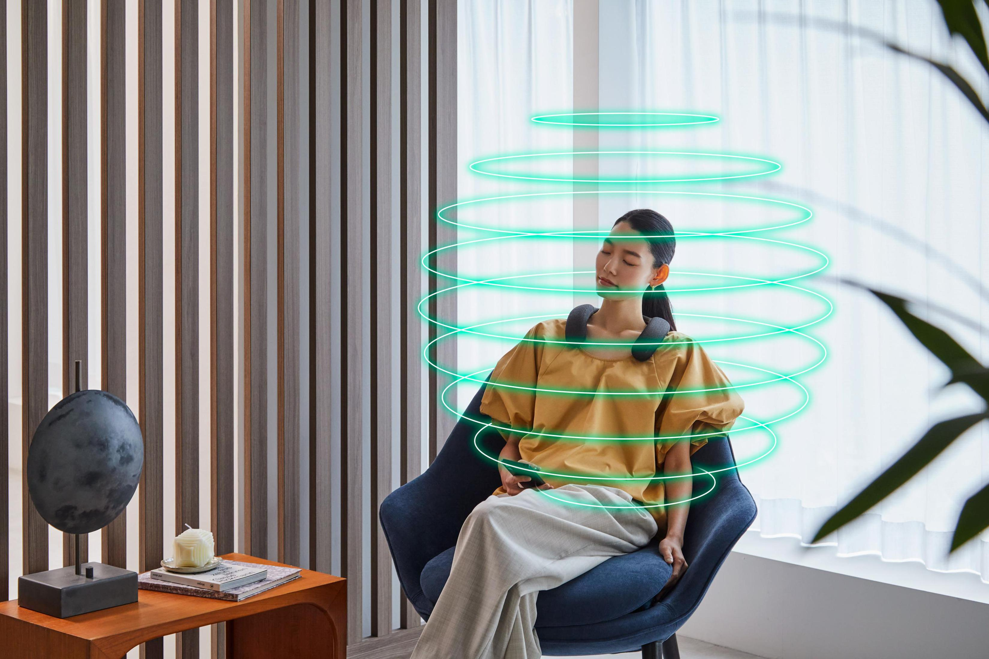 Frau mit Nackenmassagegerät, grüne Energiereifen um sie herum.