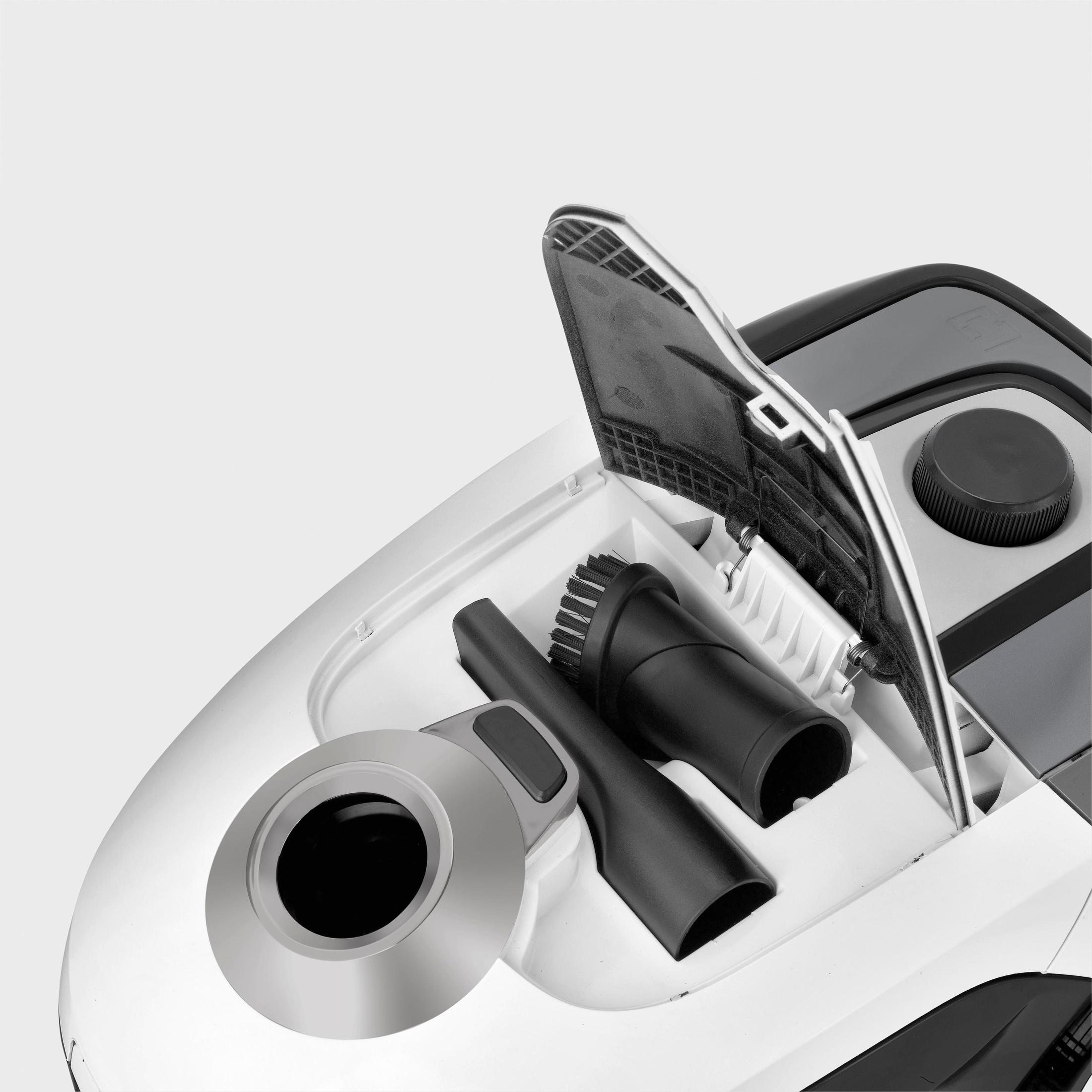 Odkurzacz z otwartą komorą, zawierający czarne akcesoria, na białym tle.