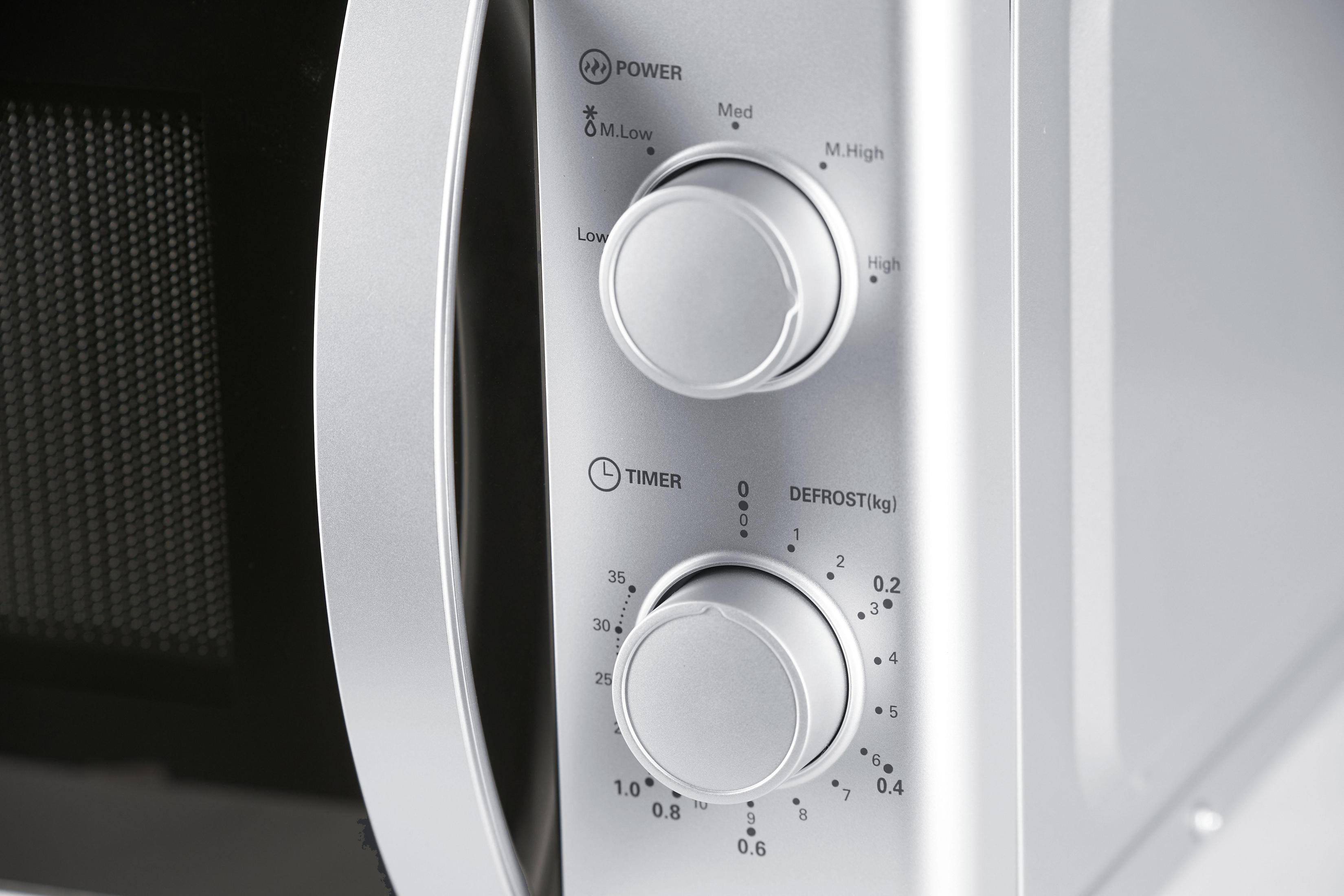 Close-up of microwave control panel. Knobs for power, timer, and defrost, all labeled.