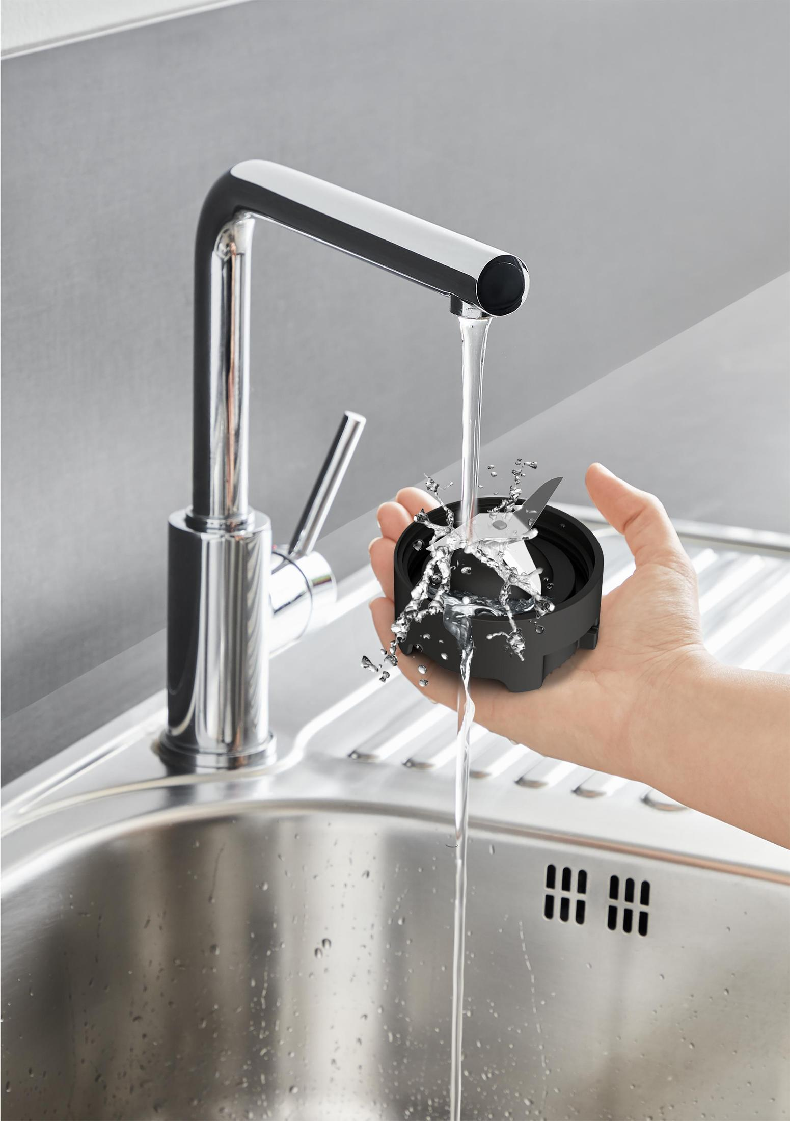 Una mano che tiene una lama del frullatore sotto un rubinetto. L'acqua scorre sulla lama.