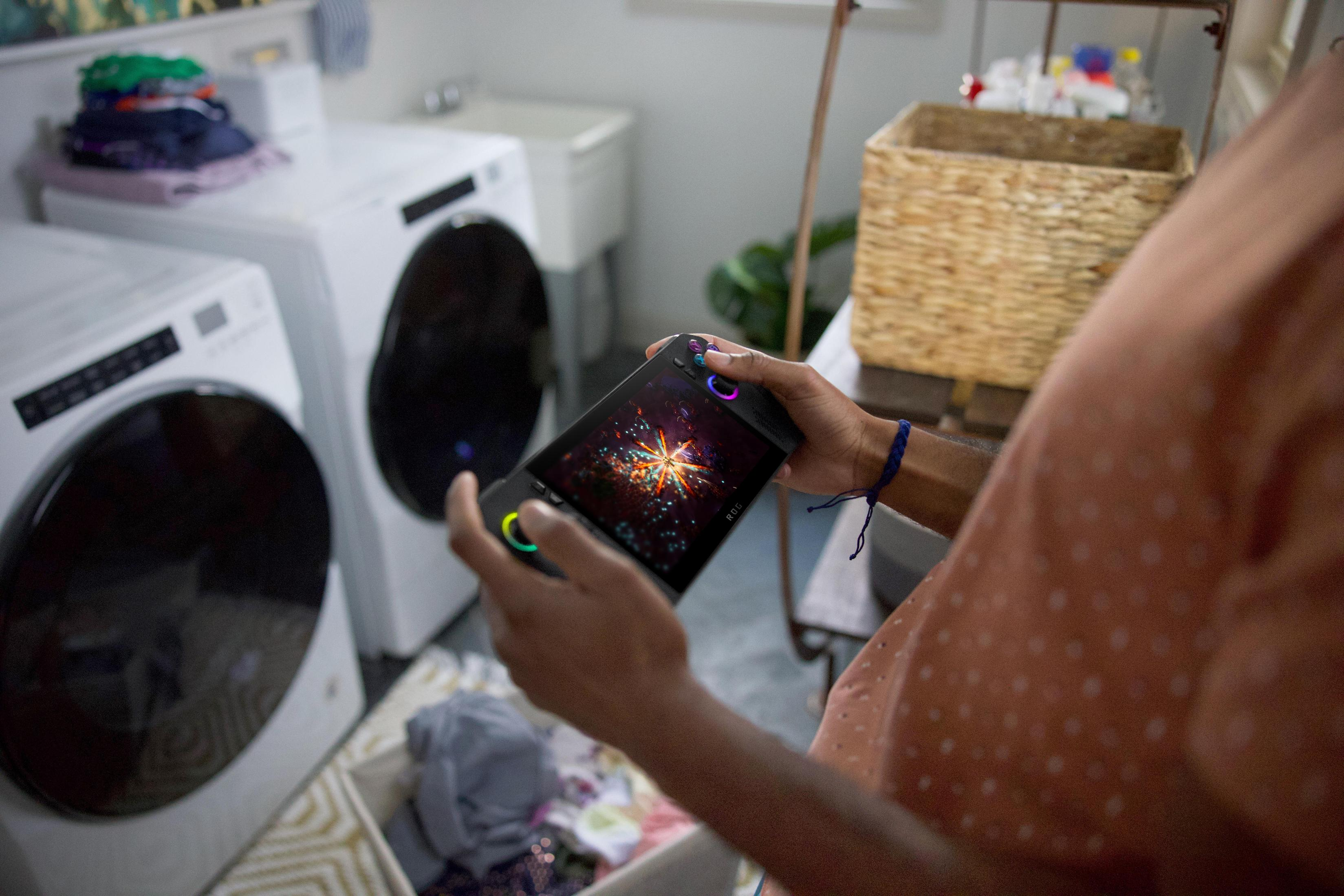 Osoba trzymająca urządzenie do gier z kolorowym ekranem. Pranie w tle.