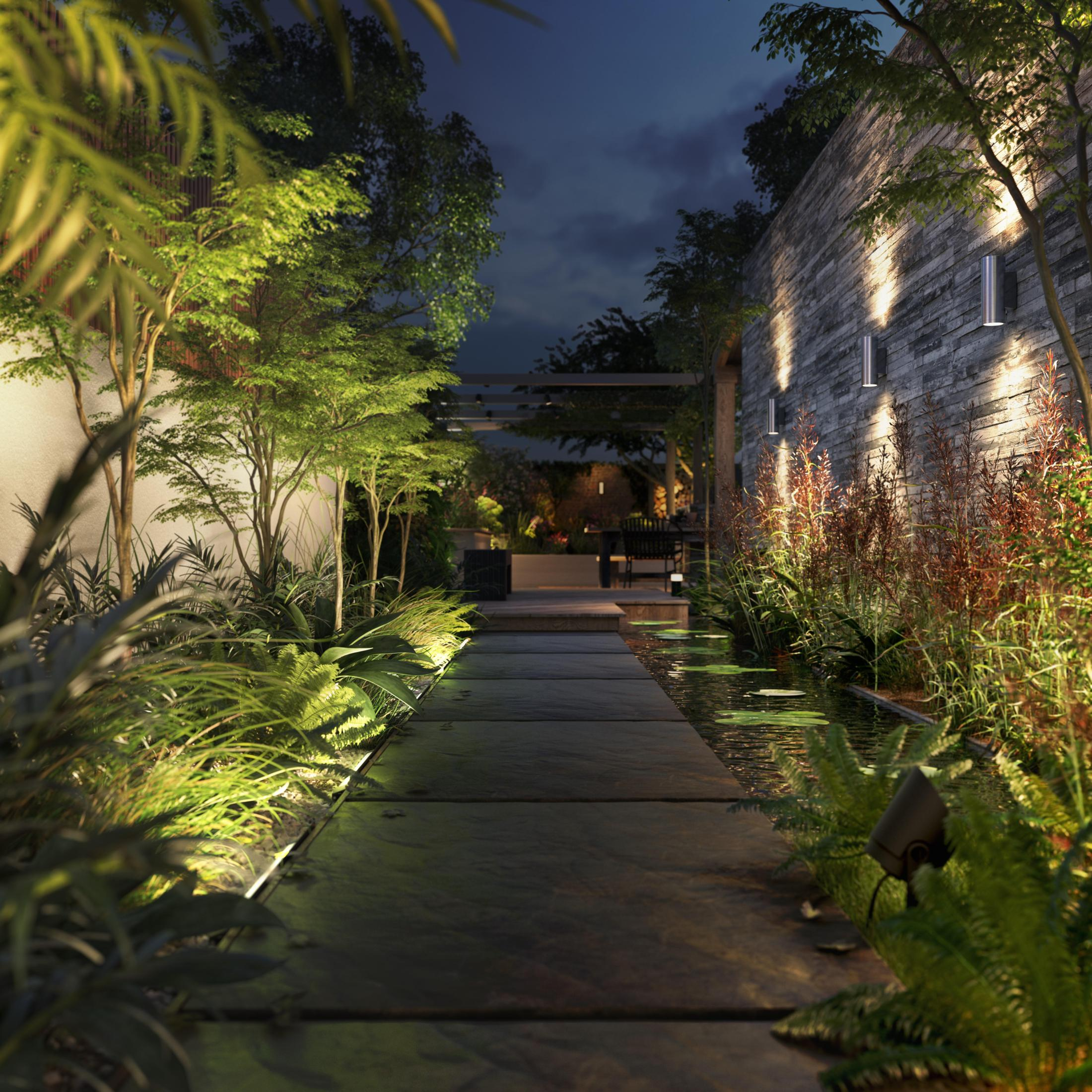 Nachtszenen eines Gartenweges, beleuchtet von Lichtern, mit Pflanzen und Wasser.