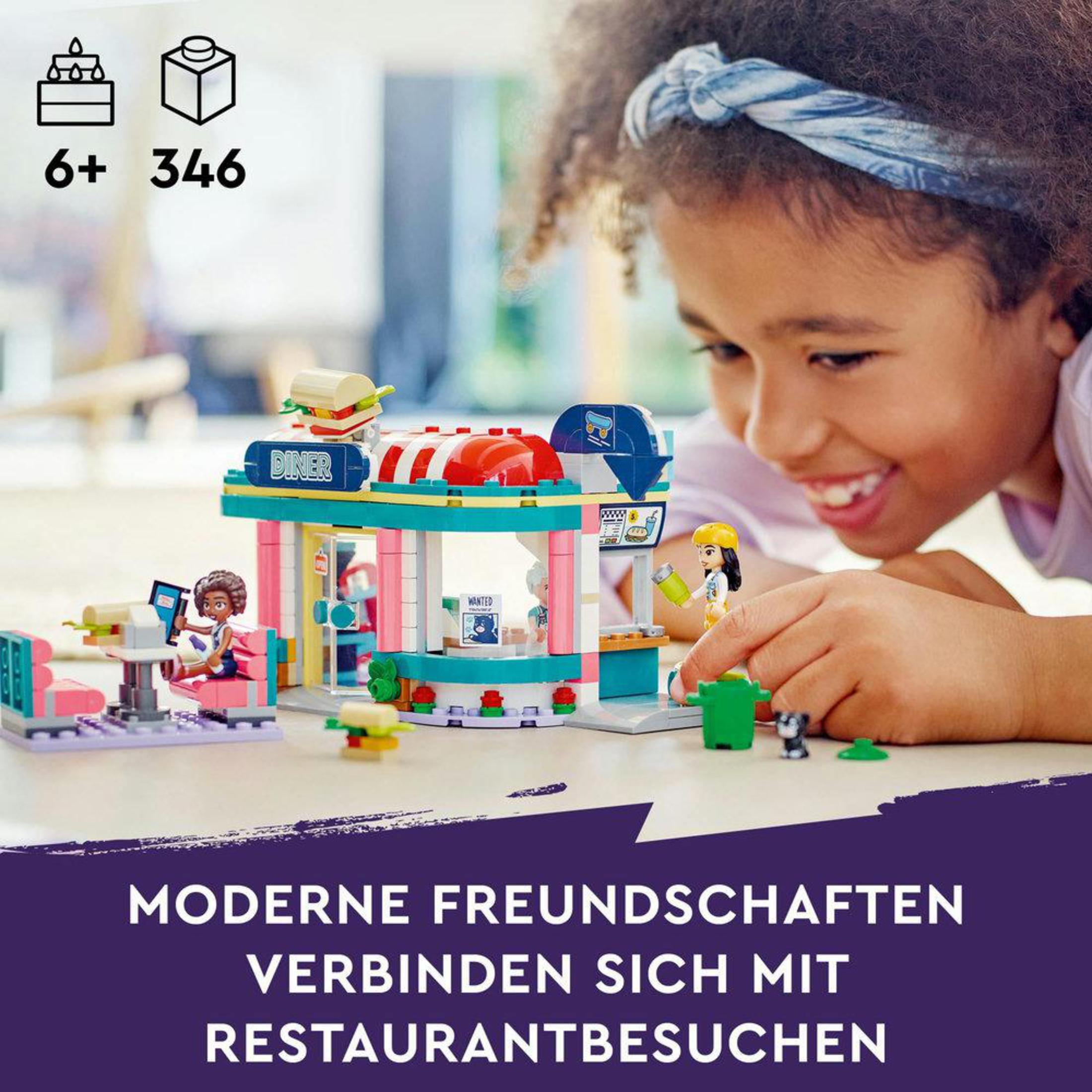 Lego-Set mit einem Diner. Ein Mädchen lächelt. Lego-Figuren interagieren. Weißer Hintergrund.