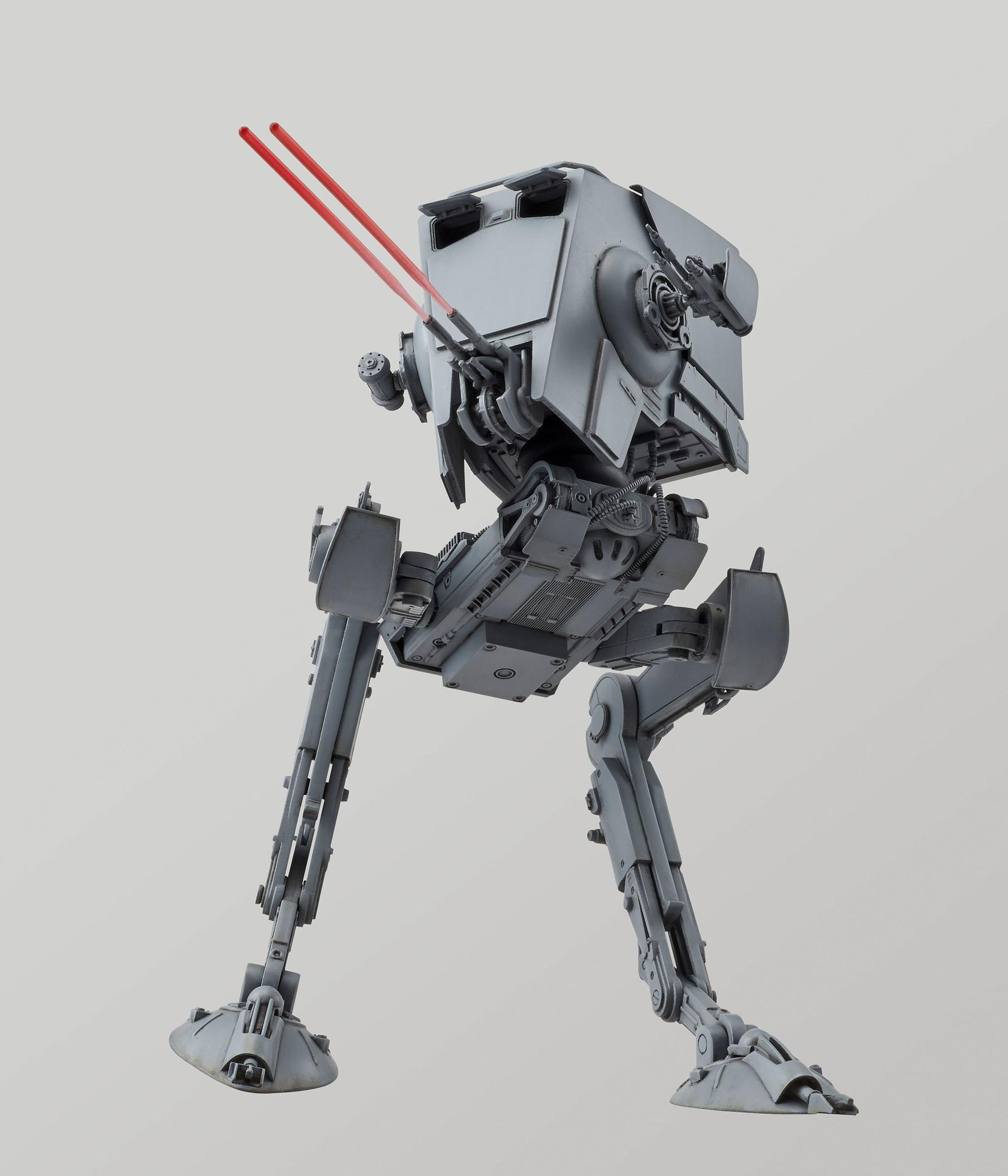 Un modèle gris d'AT-ST Walker avec des rayons laser rouges, posé sur fond blanc.
