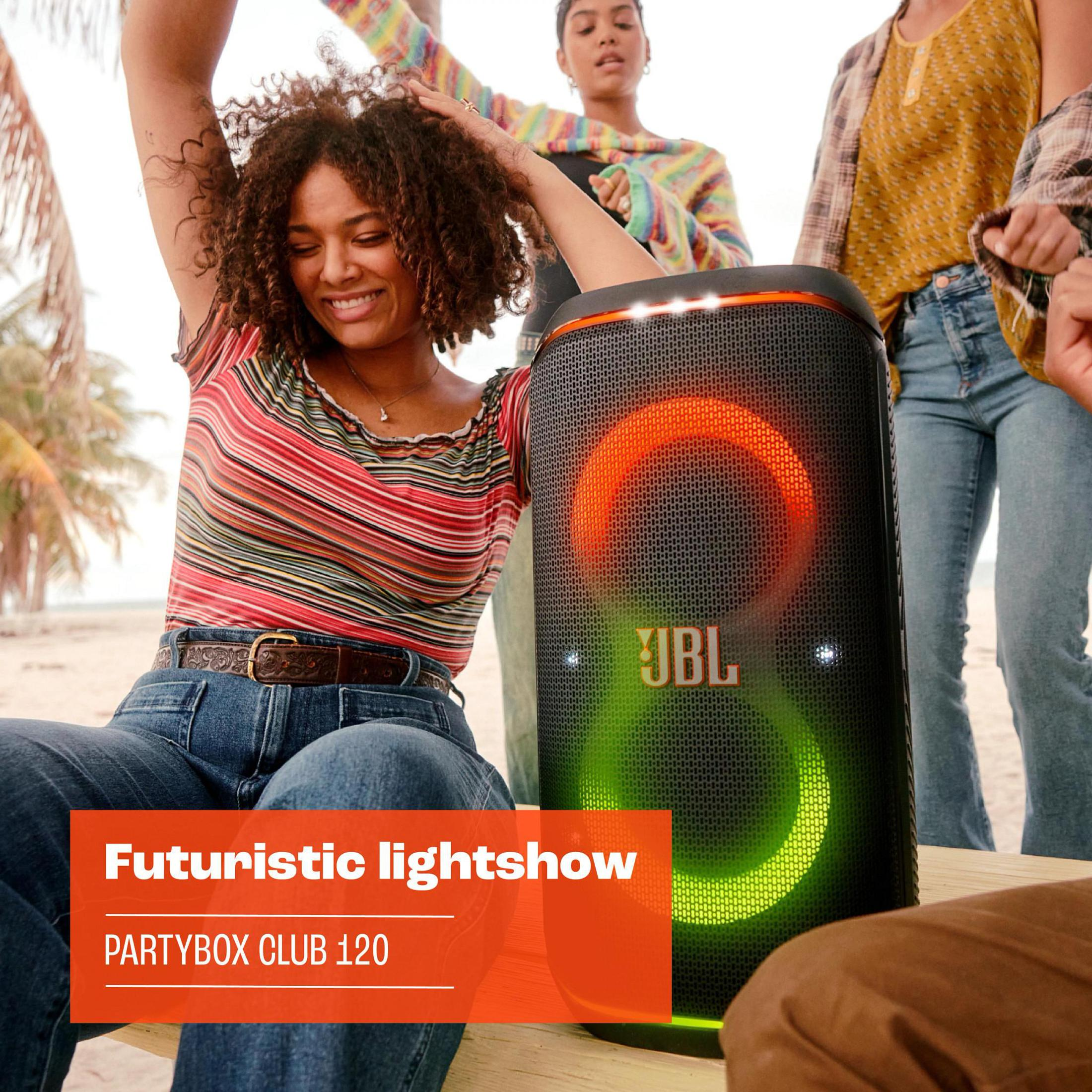Leute tanzen um einen JBL-Lautsprecher. Der Lautsprecher hat eine Lichtshow, Text: Partybox Club 120.