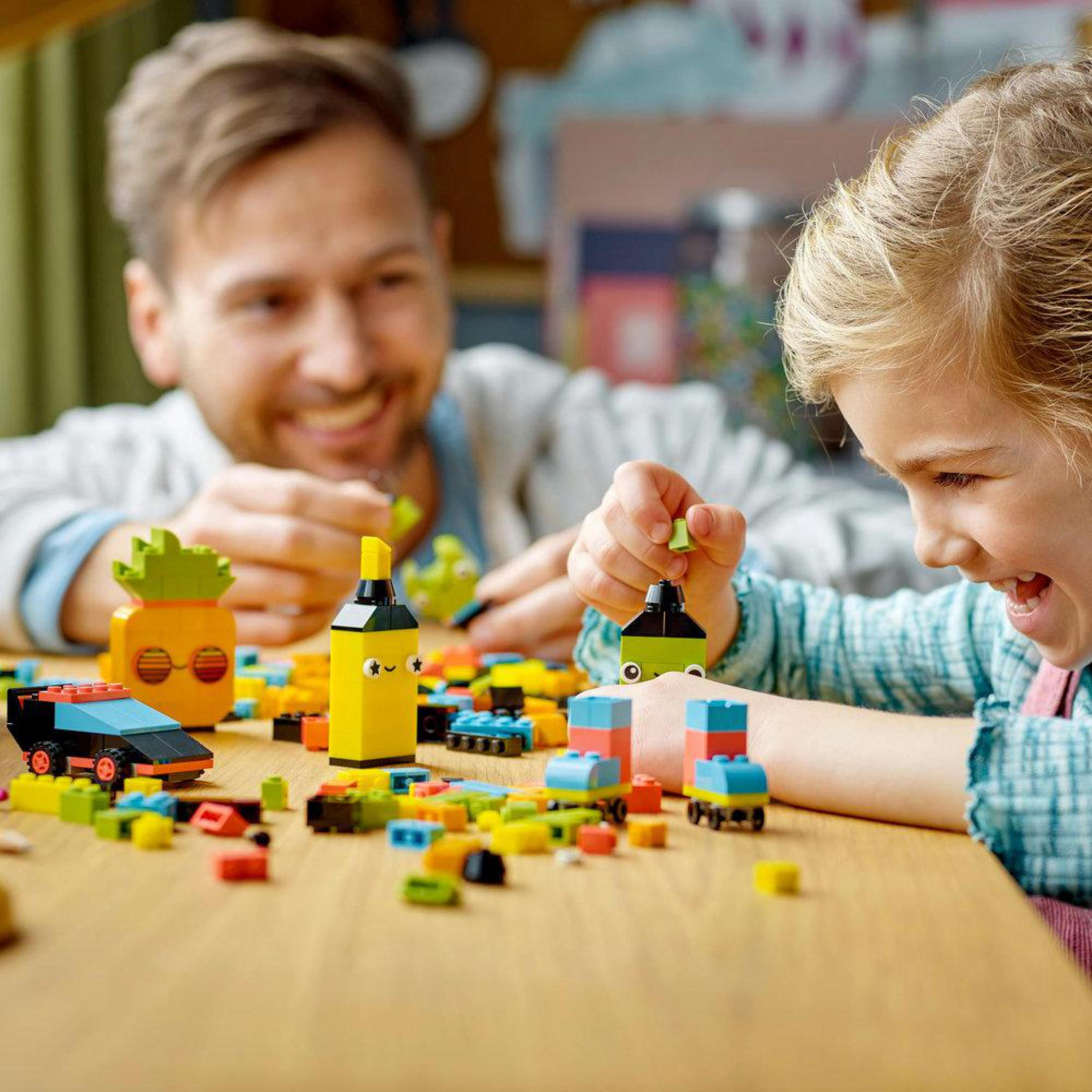 Een man en kind spelen met Lego. Kleurrijke blokken op een houten tafel.
