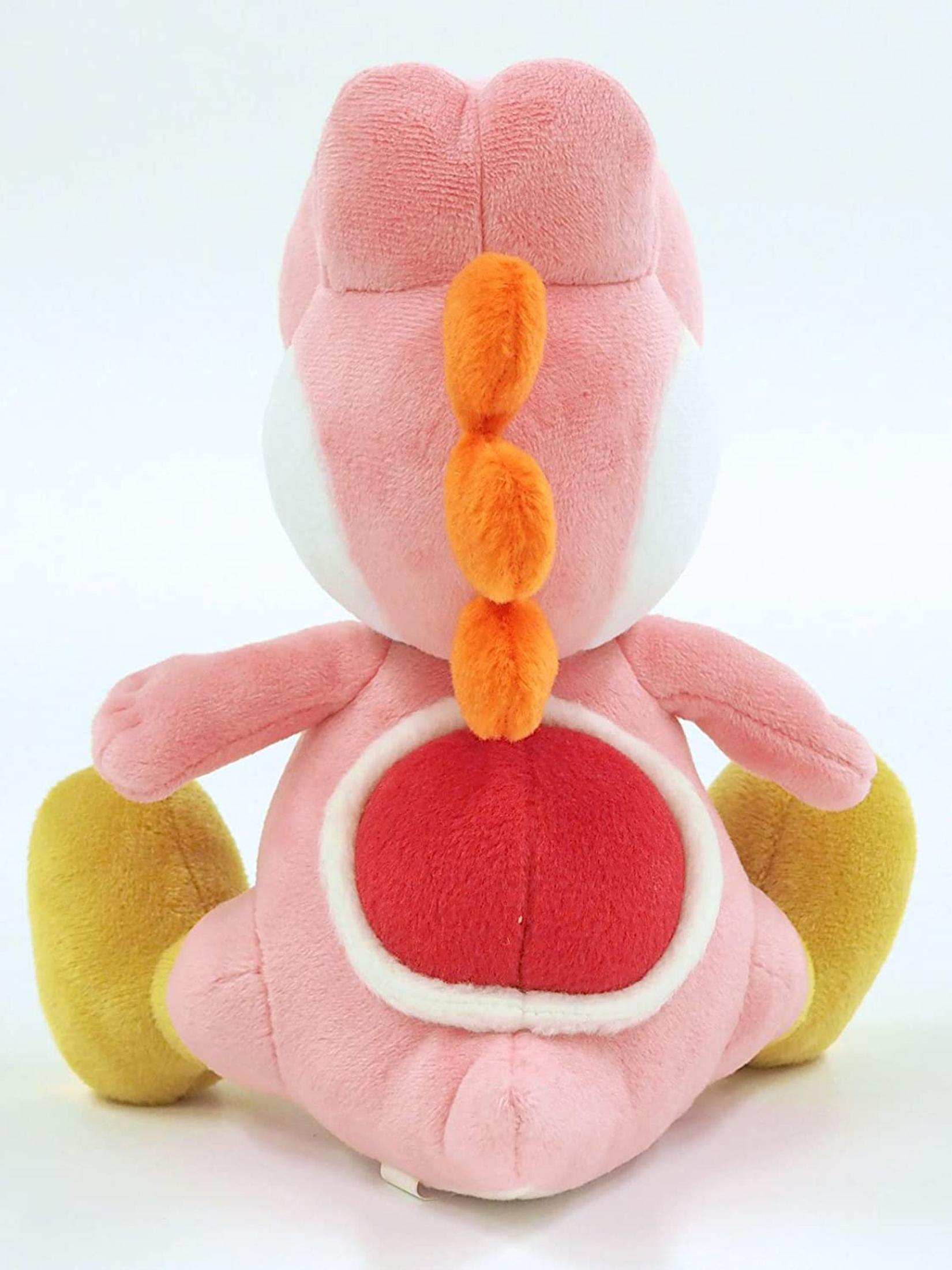 Une peluche Yoshi rose de dos. Il a des pointes orange, des chaussures jaunes et un ventre rouge.