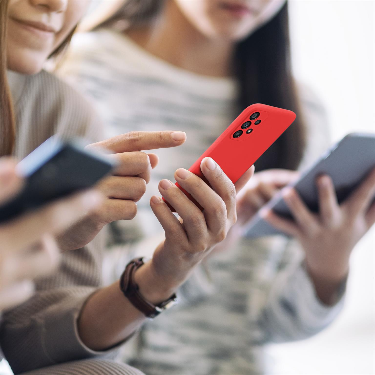 Drei Personen benutzen Telefone. Eine Person hält ein rotes Telefon.