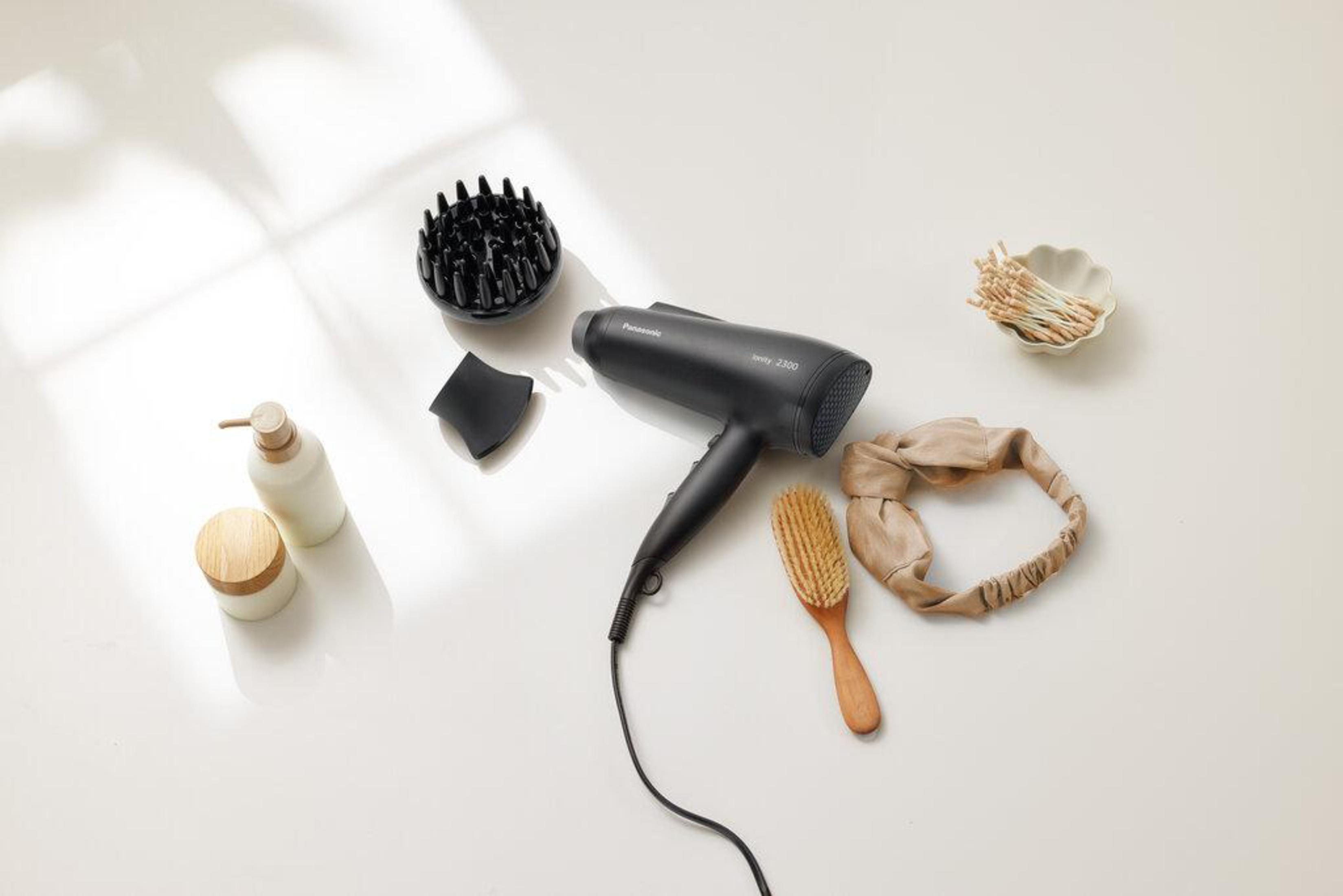 Suszarka do włosów, dyfuzor, szczotka, opaska i inne przedmioty na białej powierzchni.