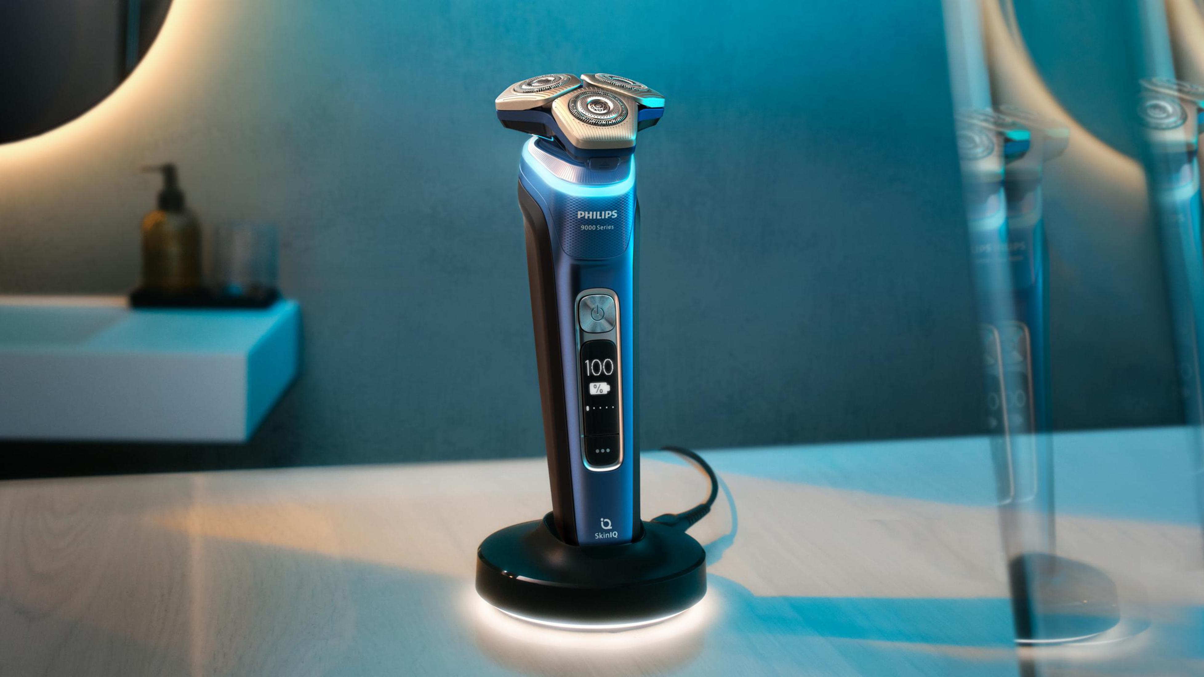 Ein blau-schwarzer Elektrorasierer steht auf einem schwarzen Ständer vor einem Spiegel, mit Akkuanzeige.