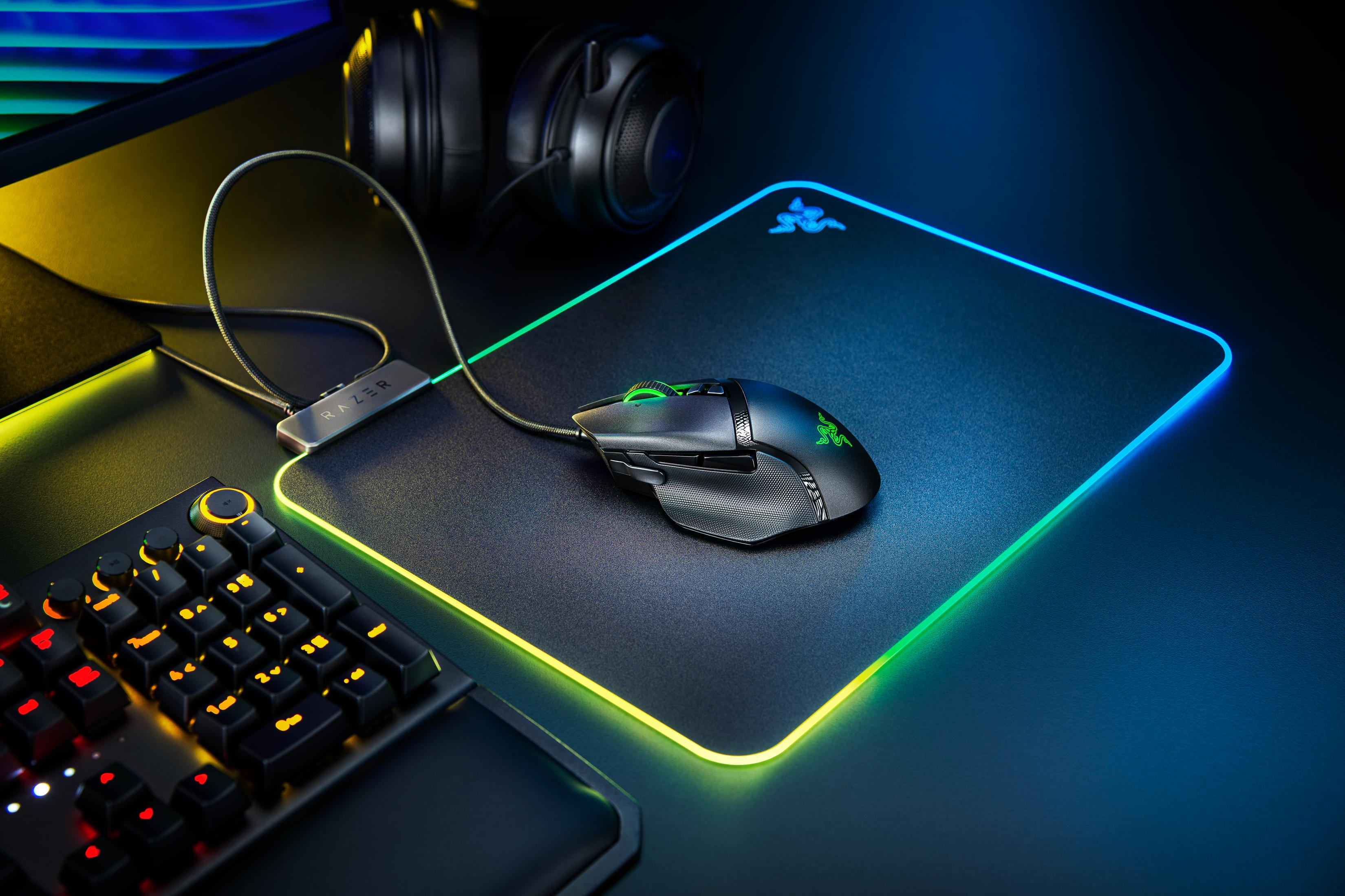 Configurazione di gioco con mouse e tappetino. Tastiera e cuffie sullo sfondo.