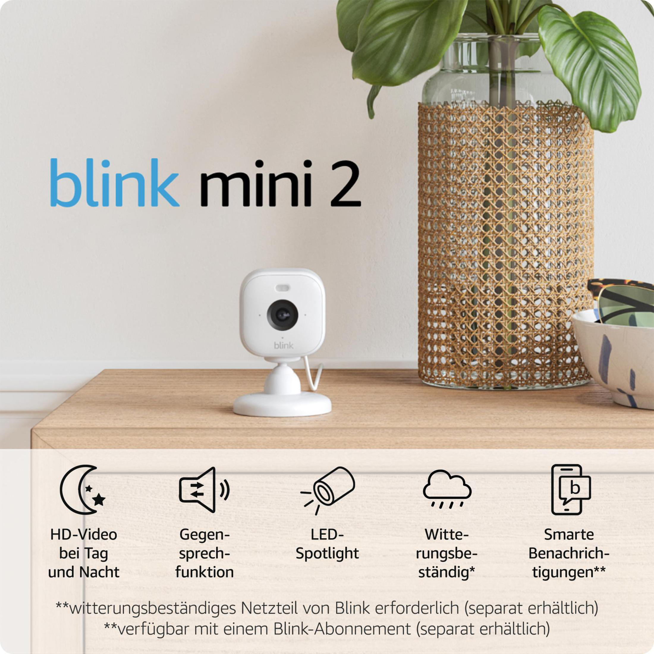 Kamera Blink mini 2 na drewnianej powierzchni, z cechami produktu: wideo HD, głośnik, reflektor LED.