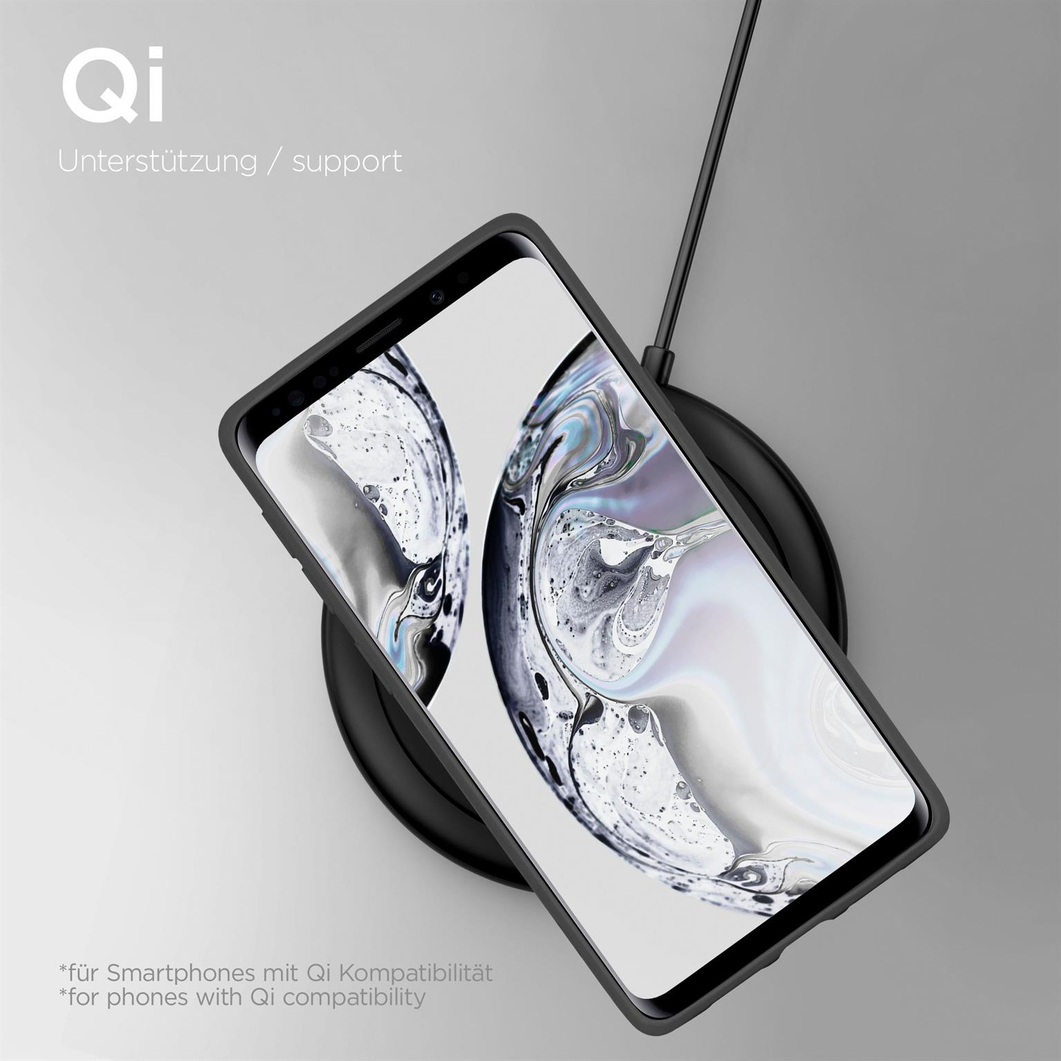 Schwarzes Telefon auf kabellosem Ladegerät. Schwarzes Ladegerät und Handyhülle. Grauer Hintergrund.