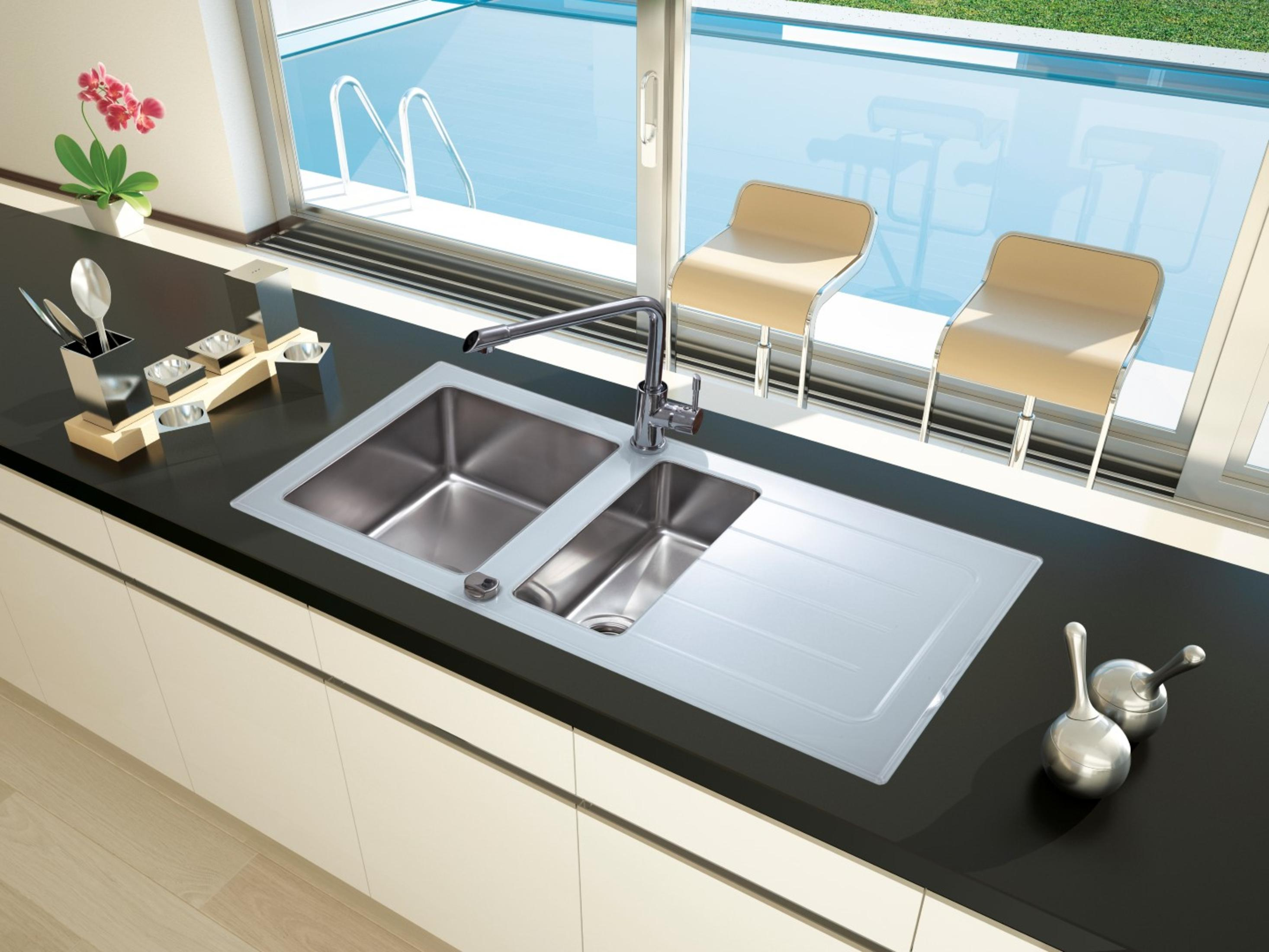 Küchenspüle mit zwei Becken und Wasserhahn. Ein Fenster und Stühle sind im Hintergrund.
