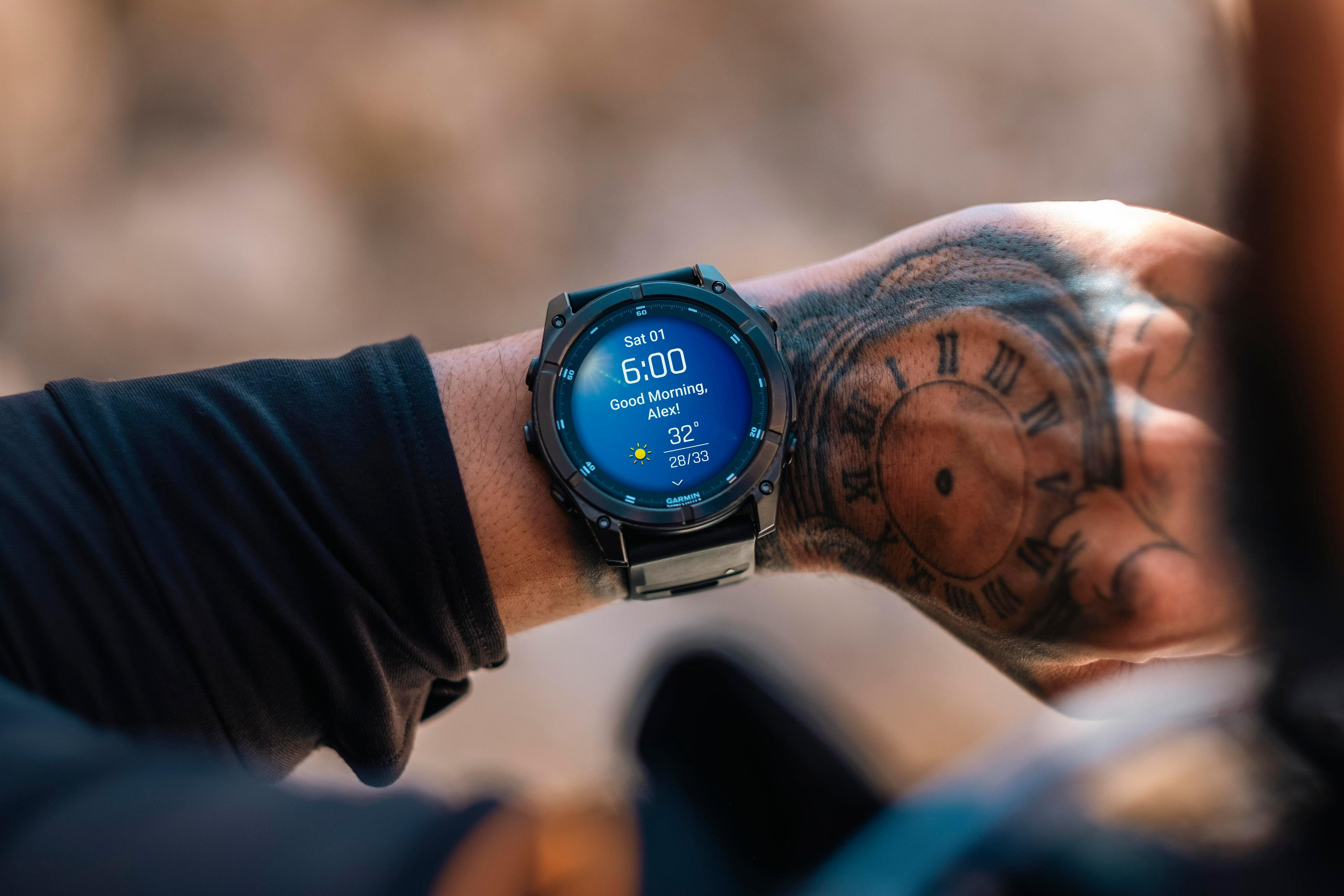 Una persona con un reloj inteligente, mostrando hora y clima, y un tatuaje en la mano.