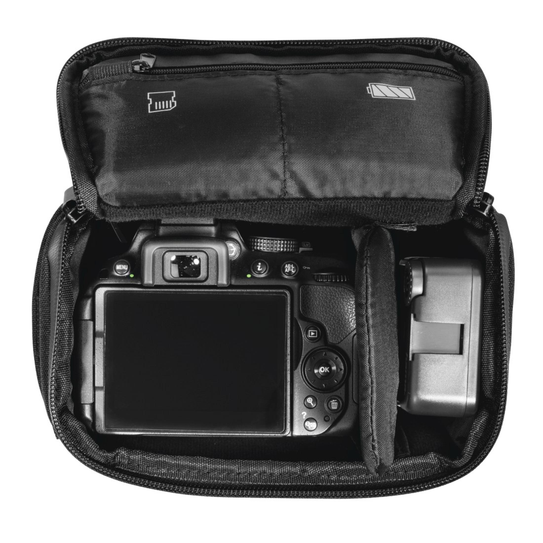 Fotocamera nera in una custodia. L'obiettivo è rivolto verso l'alto. Un caricabatterie laterale.