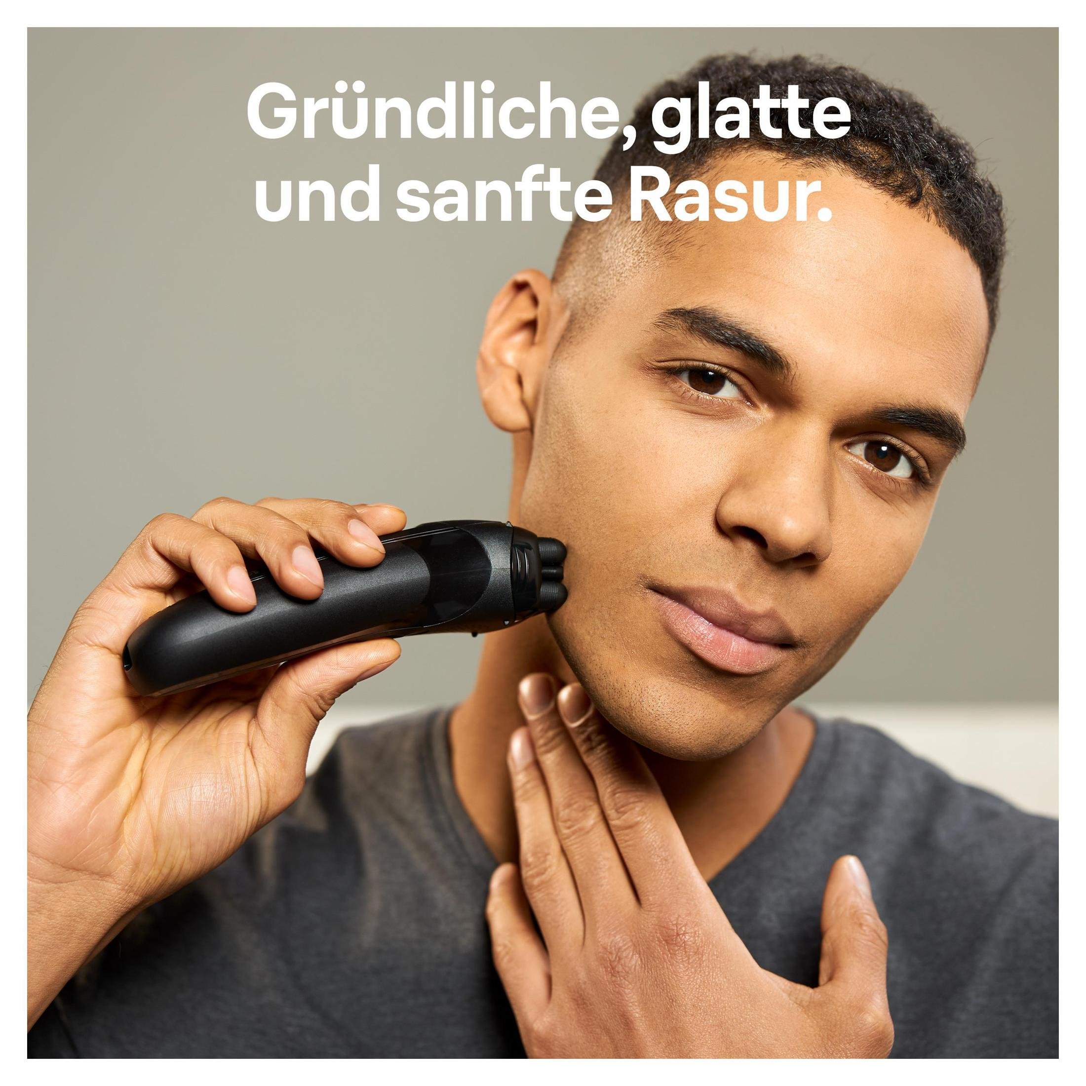 Mężczyzna golący twarz czarną golarką elektryczną.