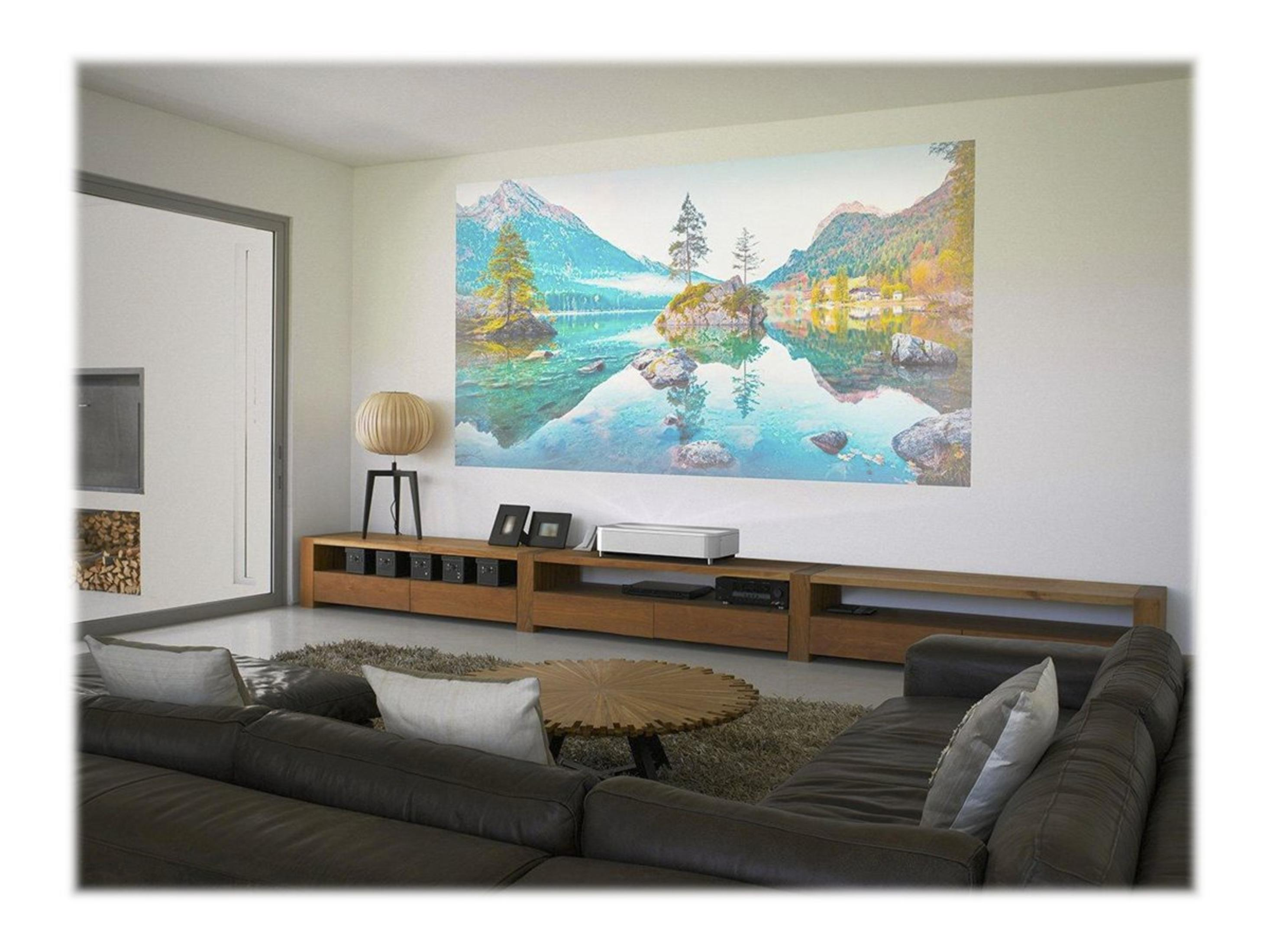 Salon z projektorem wyświetlającym scenę górską i jeziorną na ścianie.