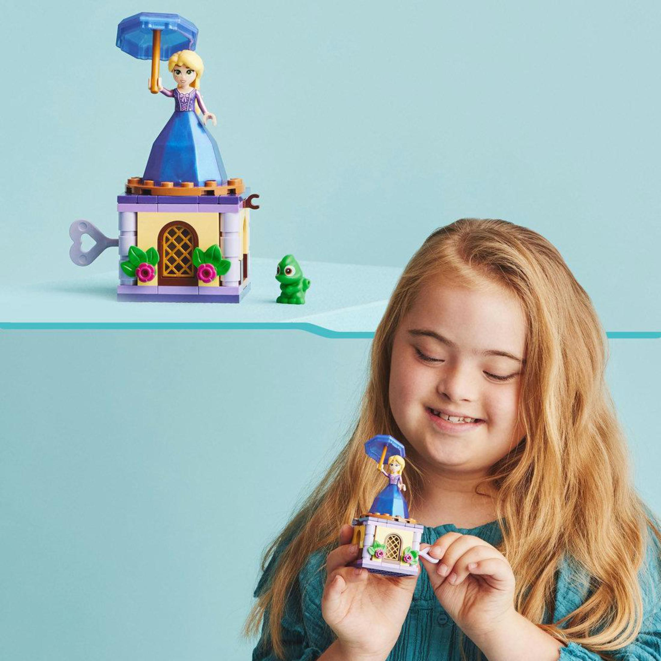 Mädchen mit Down-Syndrom hält Spielzeugschloss mit Puppe und grüner Eidechse.