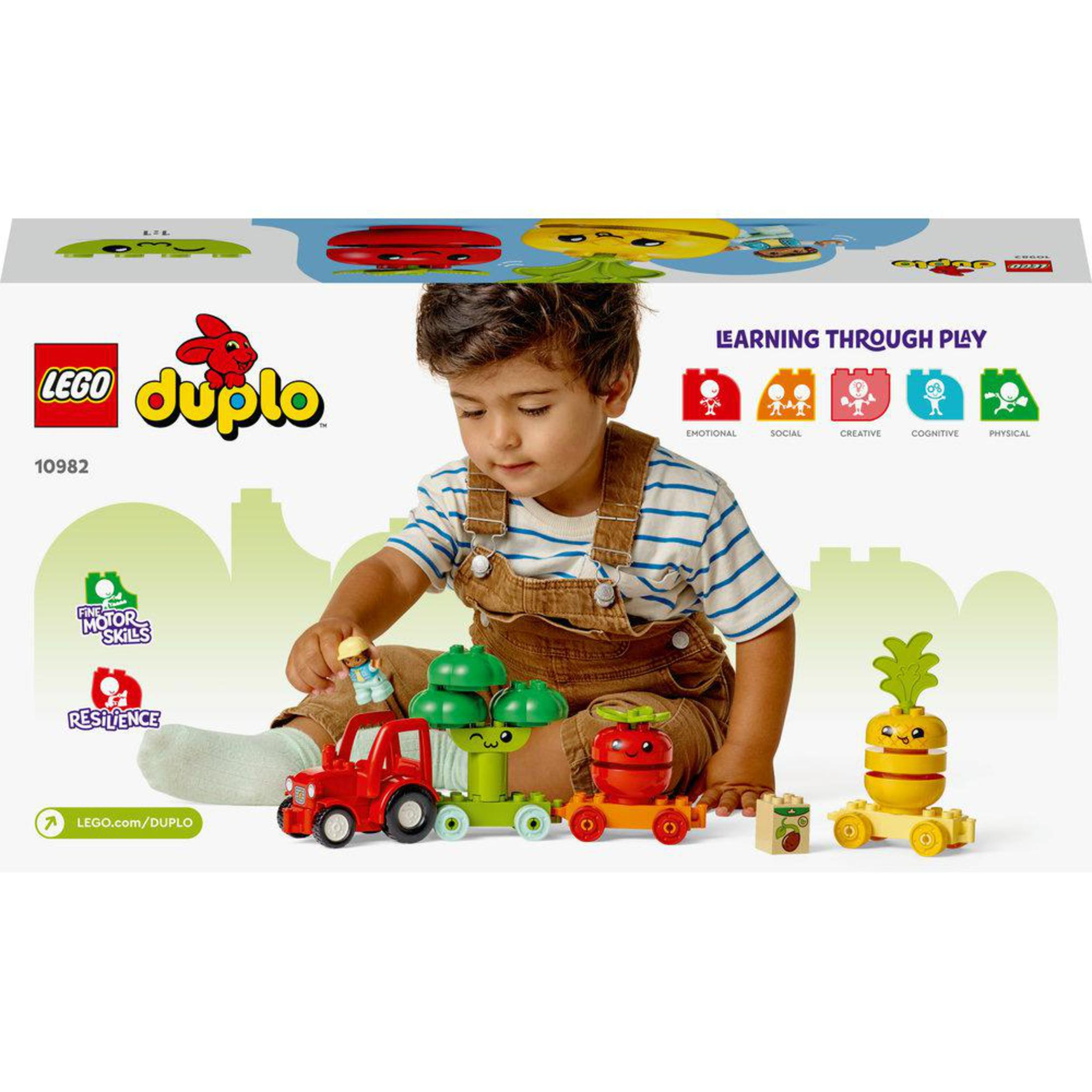 Un bambino gioca con un set Lego Duplo. Il set include un treno e figure di verdure.