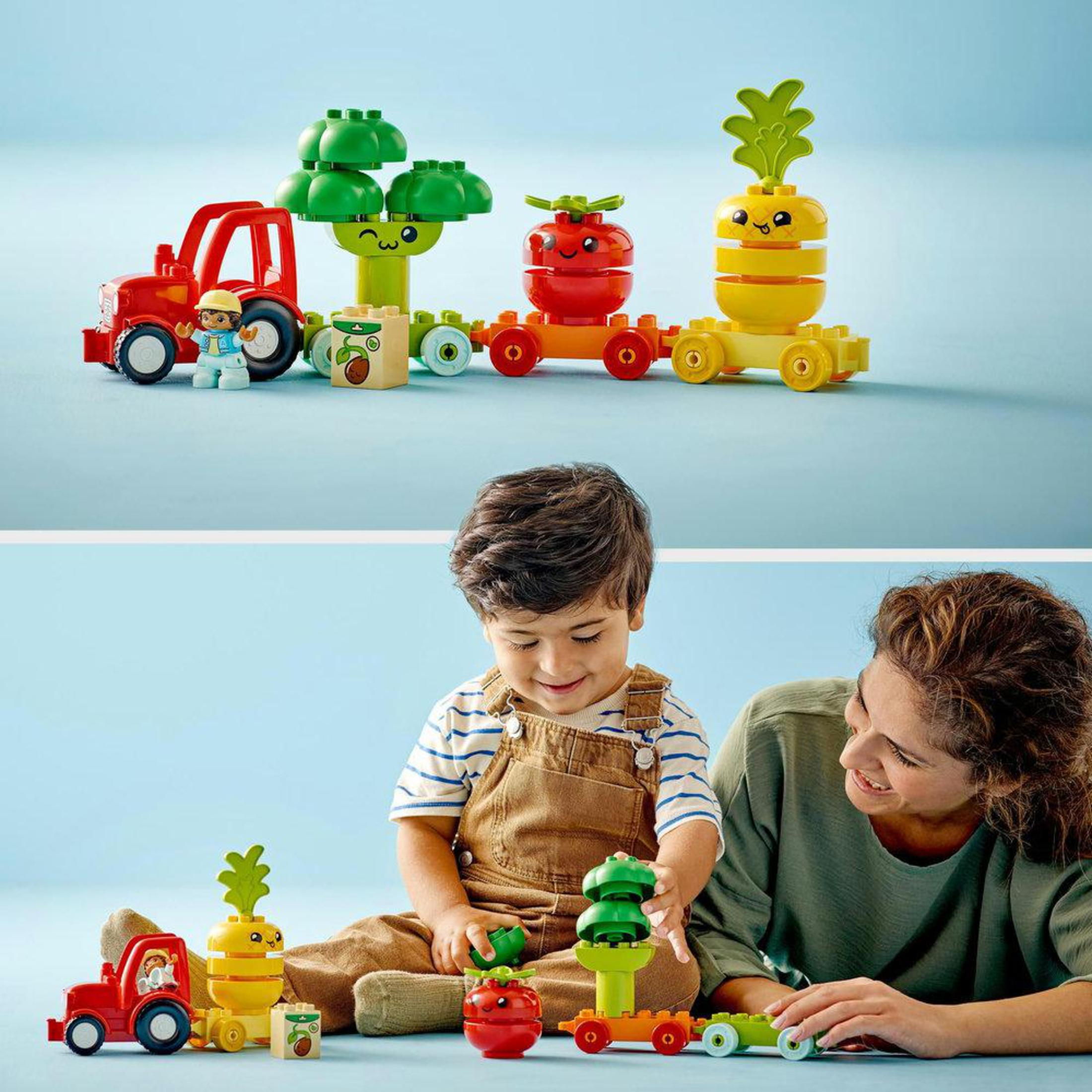Un bambino e un adulto giocano con un trenino Lego con verdure. Sfondo blu.