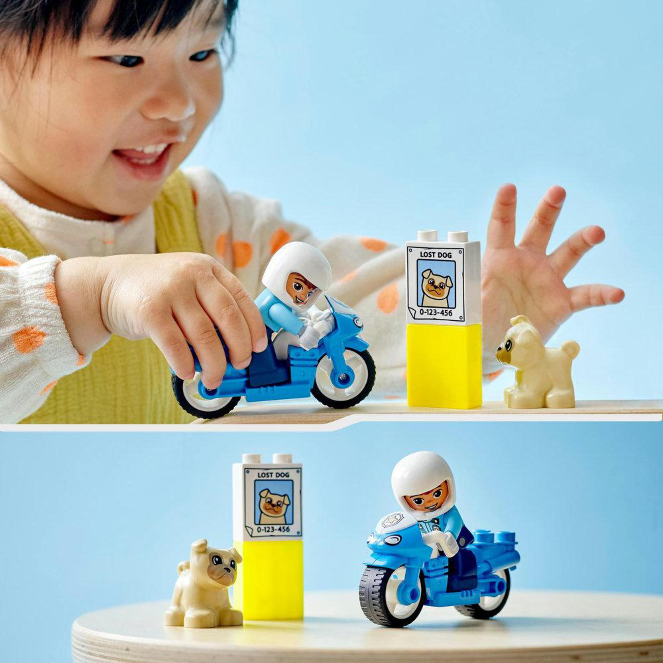 Een kind dat speelt met Lego Duplo-speelgoed, waaronder een motor, een hond en borden.