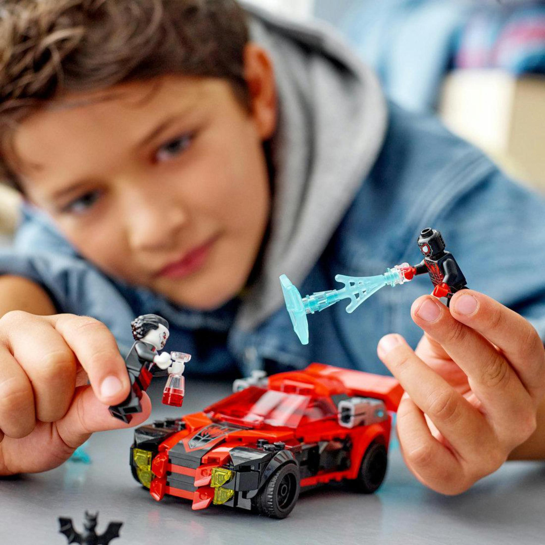 Junge spielt mit Lego-Set, Automodell und zwei Vampirfiguren mit Zubehör.