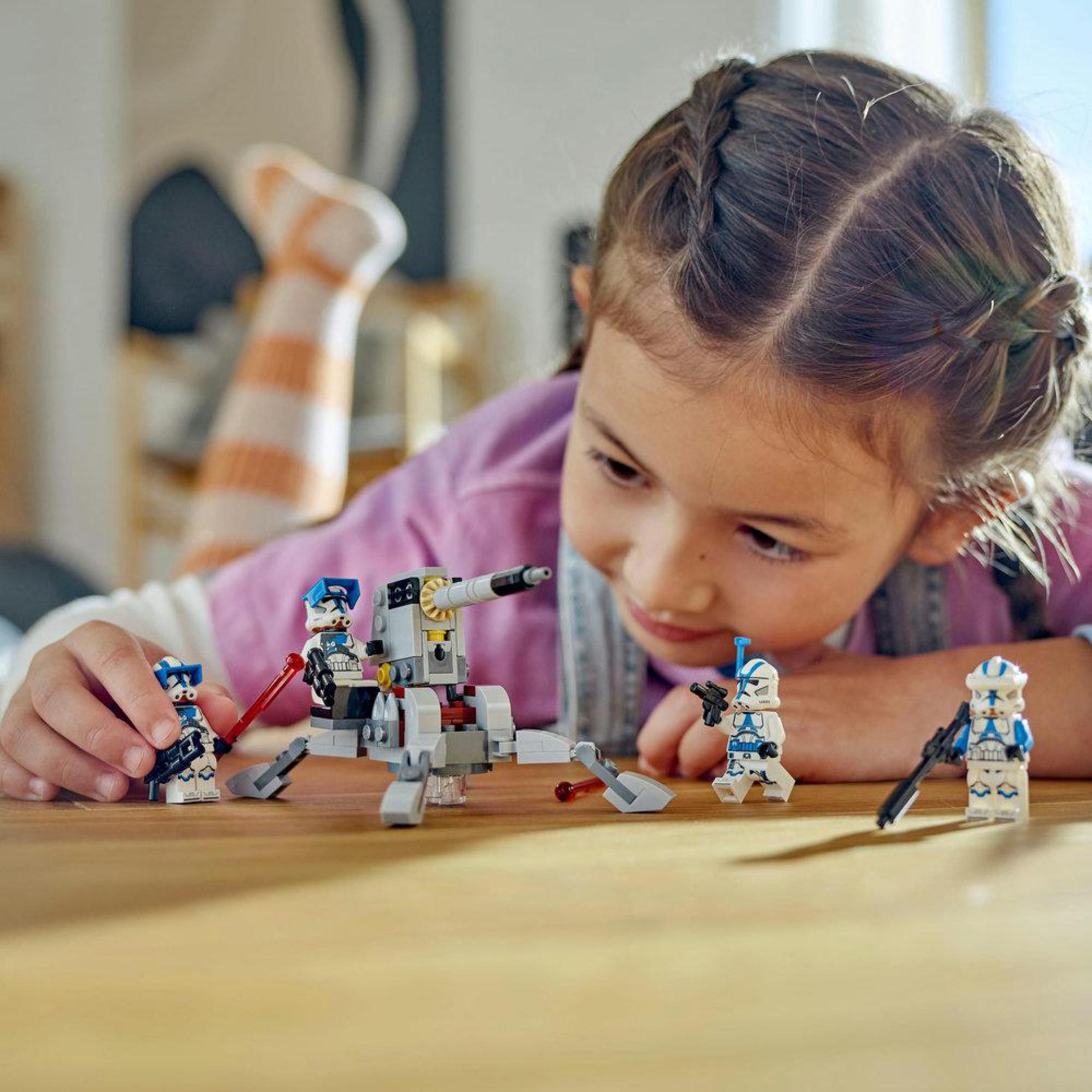 Ein Mädchen spielt mit Lego Star Wars Figuren. Sie betrachtet die Figuren lächelnd.