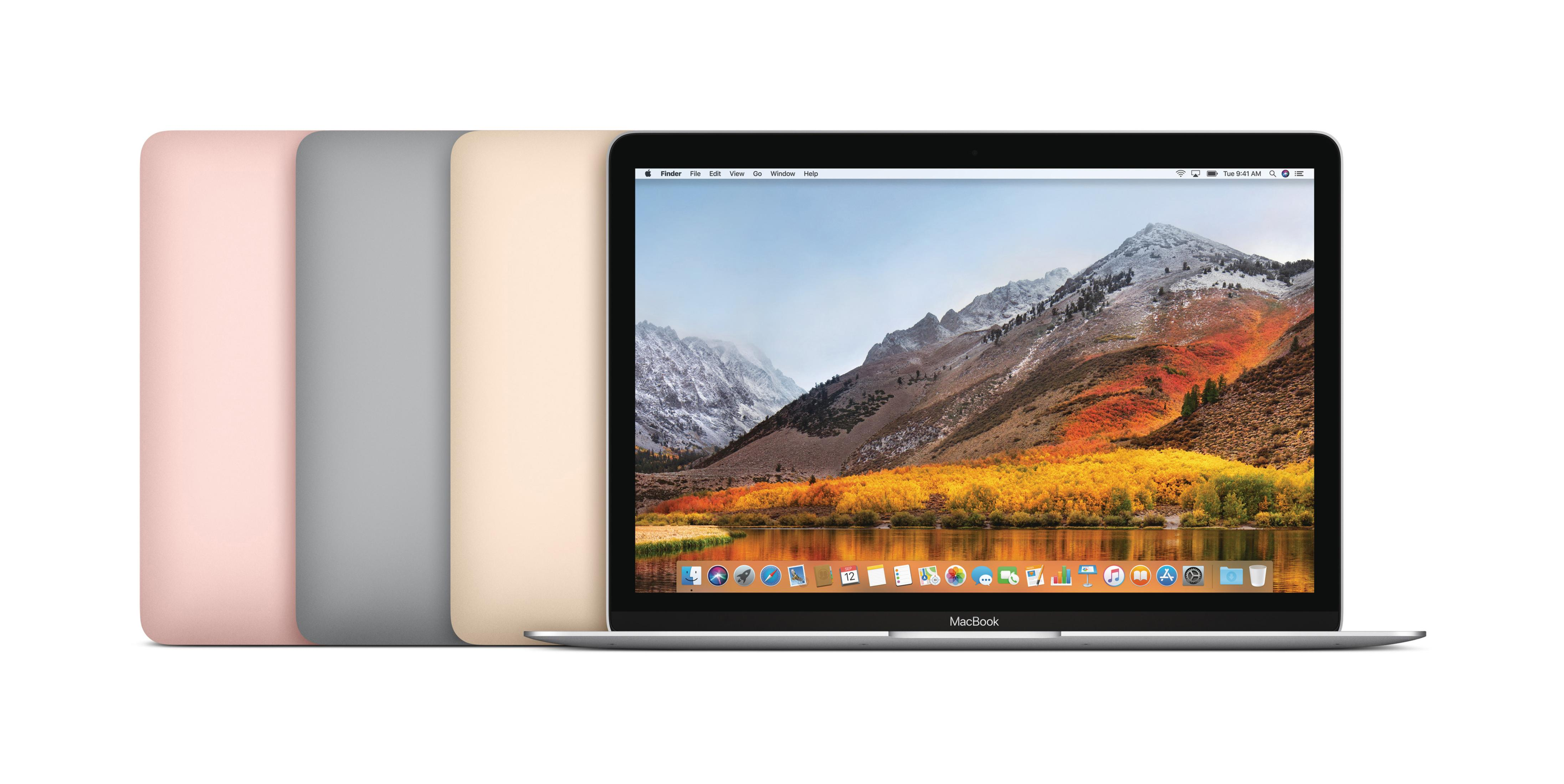 Vier farbige MacBooks auf weißer Oberfläche, der Bildschirm des ersten ist an.