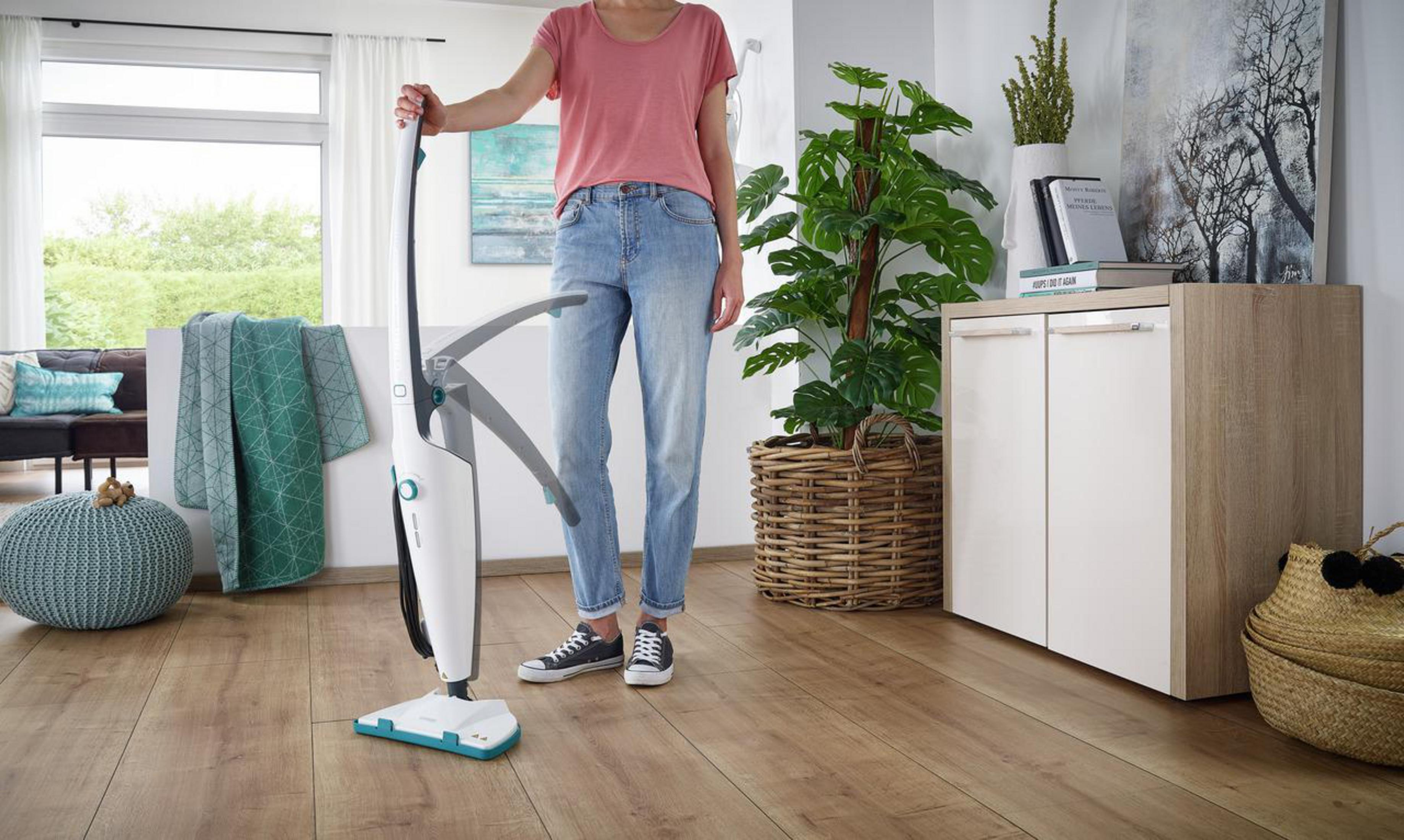 Osoba myje drewnianą podłogę białym i turkusowym mopem parowym w salonie.