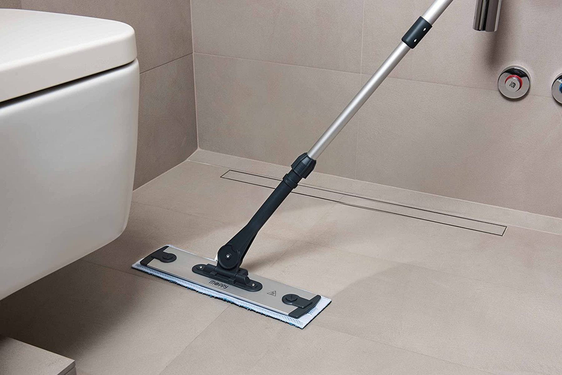 Una fregona se usa para limpiar un piso embaldosado en un baño con un inodoro.