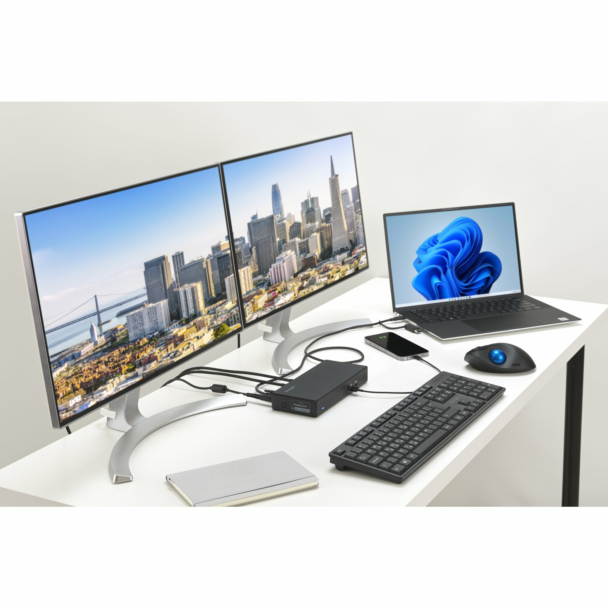 Schreibtisch mit zwei Monitoren, Laptop, Tastatur, Maus und Telefon, alles auf weißem Schreibtisch.