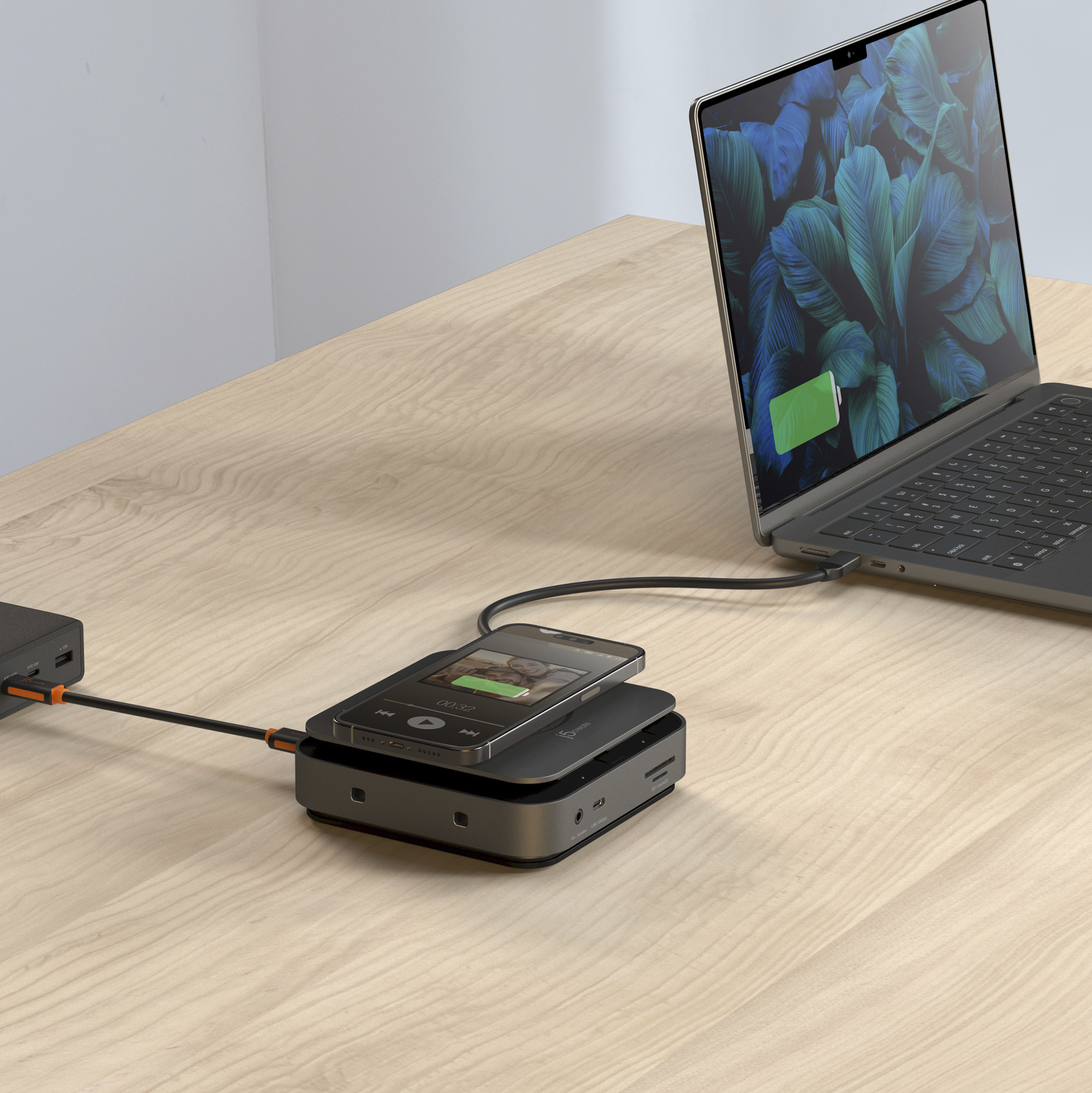 Ordinateur portable chargeant un téléphone sur une station de charge, avec une batterie externe noire.