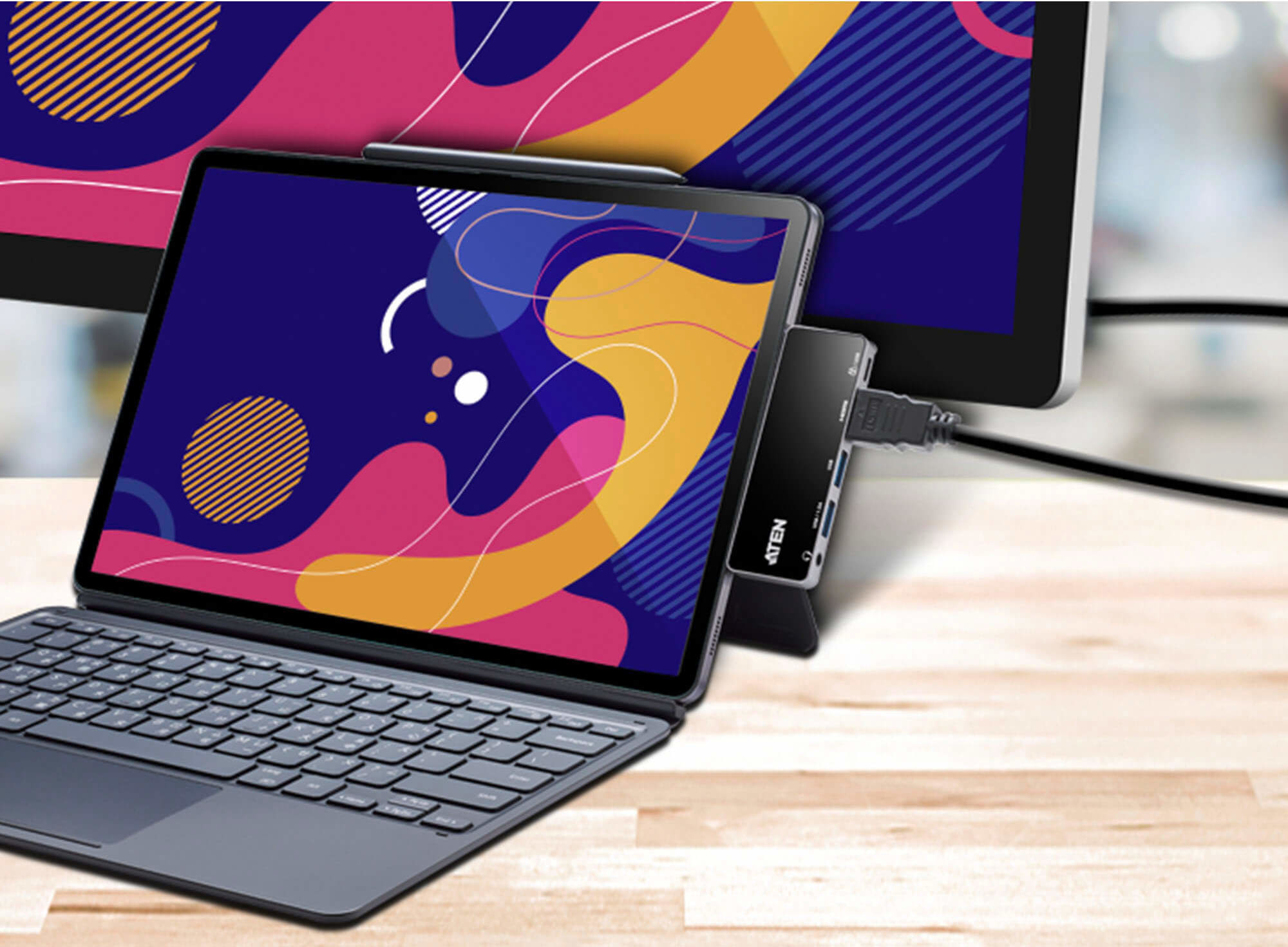 Ein Tablet, das mit einem Hub und einem Monitor mit farbenfrohem Hintergrund verbunden ist.