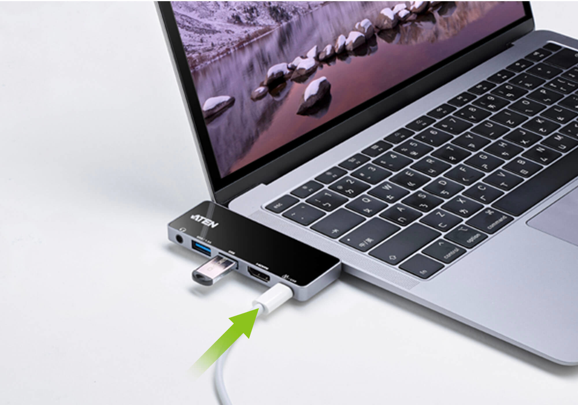 Laptop mit Hub verbunden, grüner Pfeil zeigt auf das Ladekabel.