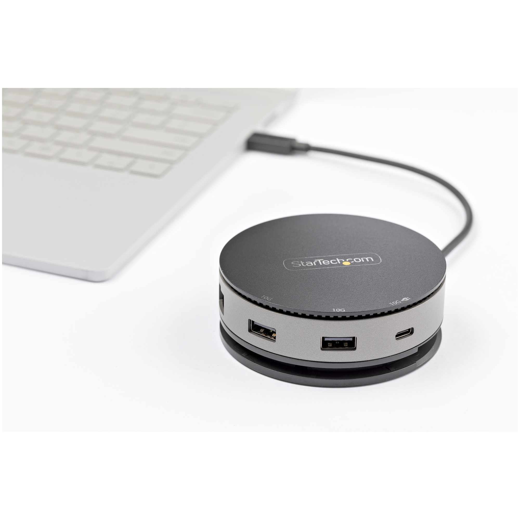 Runder, schwarzer Startech-Hub mit mehreren Anschlüssen und USB-Kabel, auf Weiß platziert.