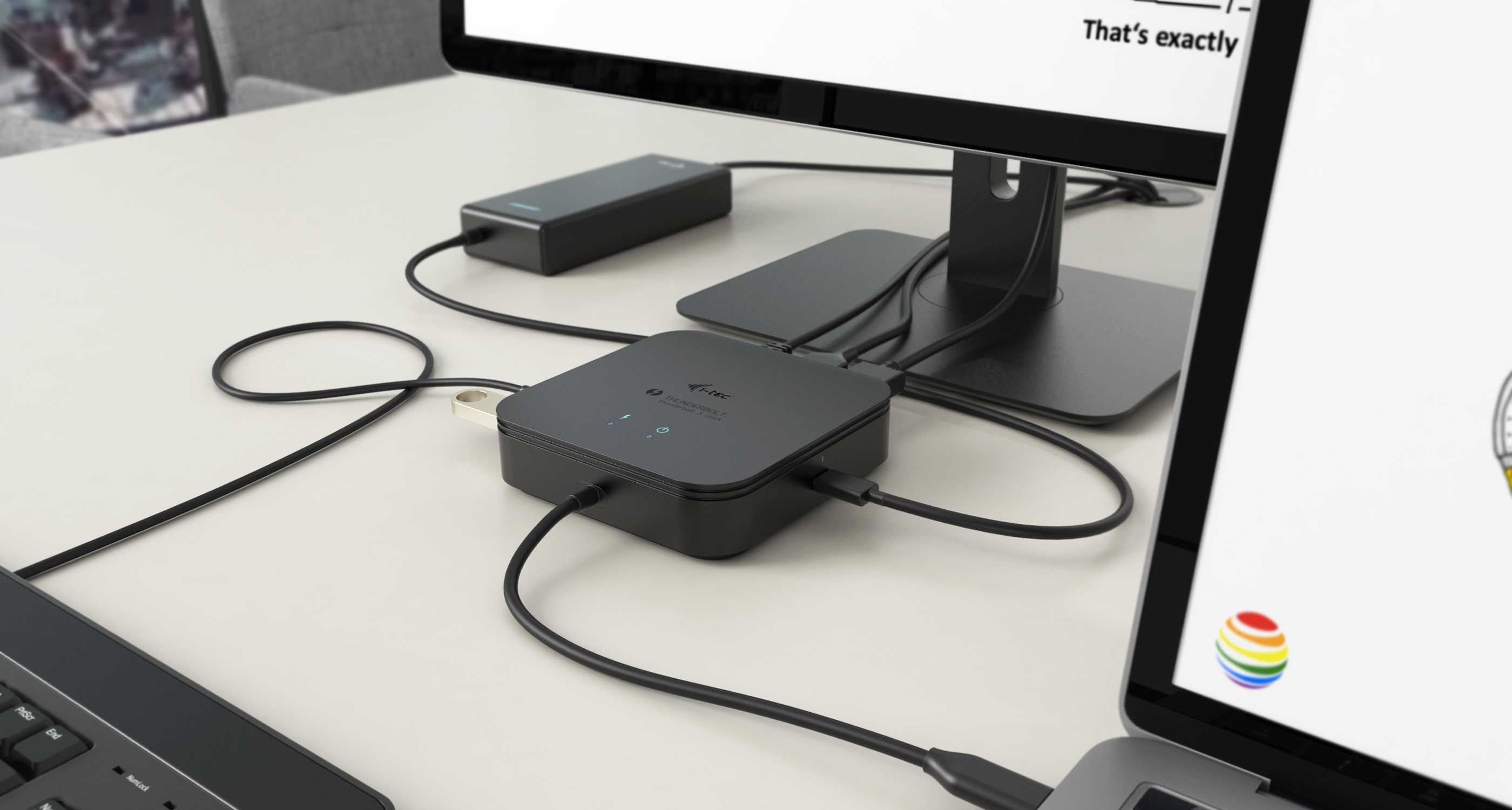 Black docking station connected to multiple monitors, keyboard, and laptop.