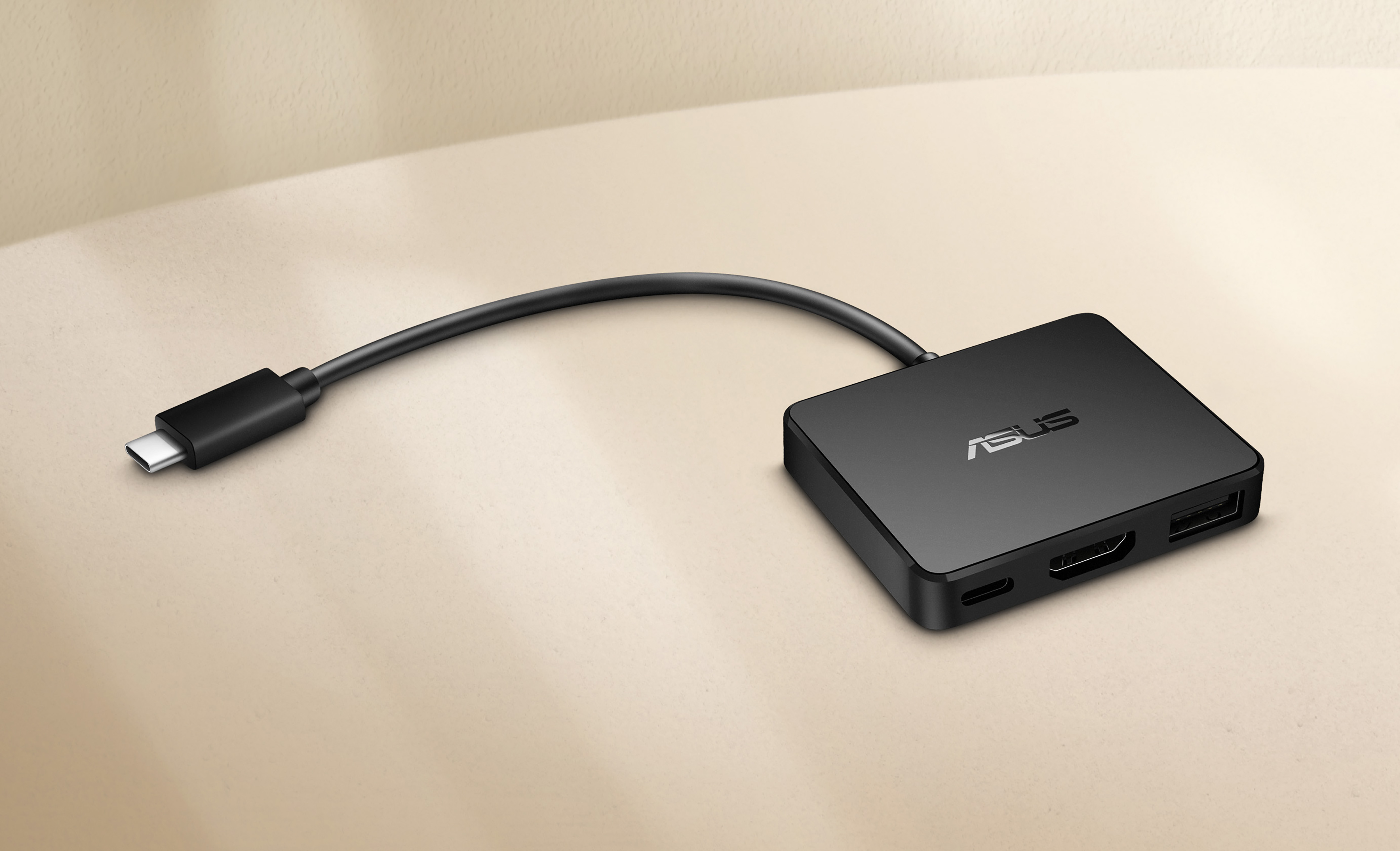 Black ASUS USB-C hub with HDMI, USB, and USB-C ports. The hub is on a table.