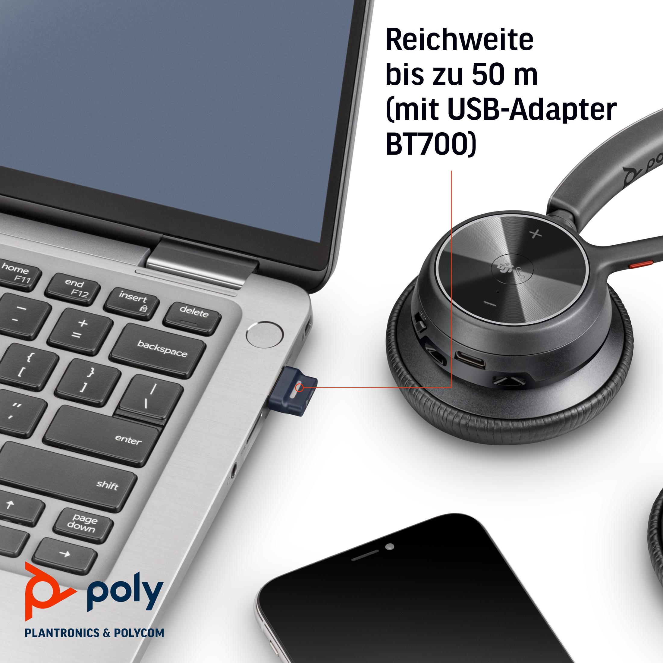 Laptop z podłączonym adapterem USB, zestaw słuchawkowy i smartfon na stole.